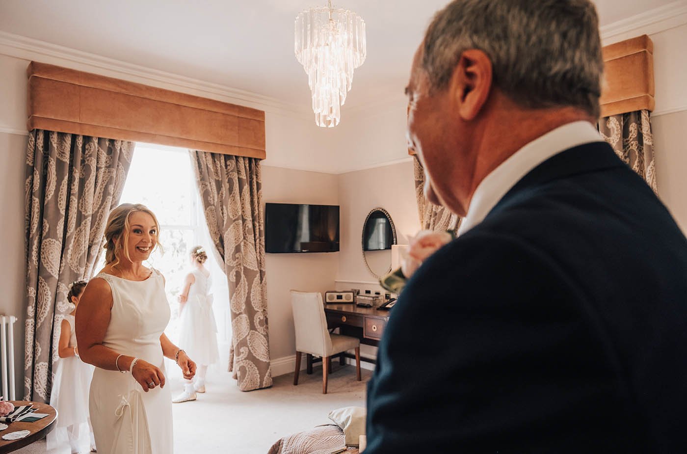 A touching moment captured at Lodore Falls, a charming wedding venue in the Lake District, as the bride greets her father on the morning of her wedding day. The bride is dressed in her bridal robe, and her father looks proud and emotional as he sees