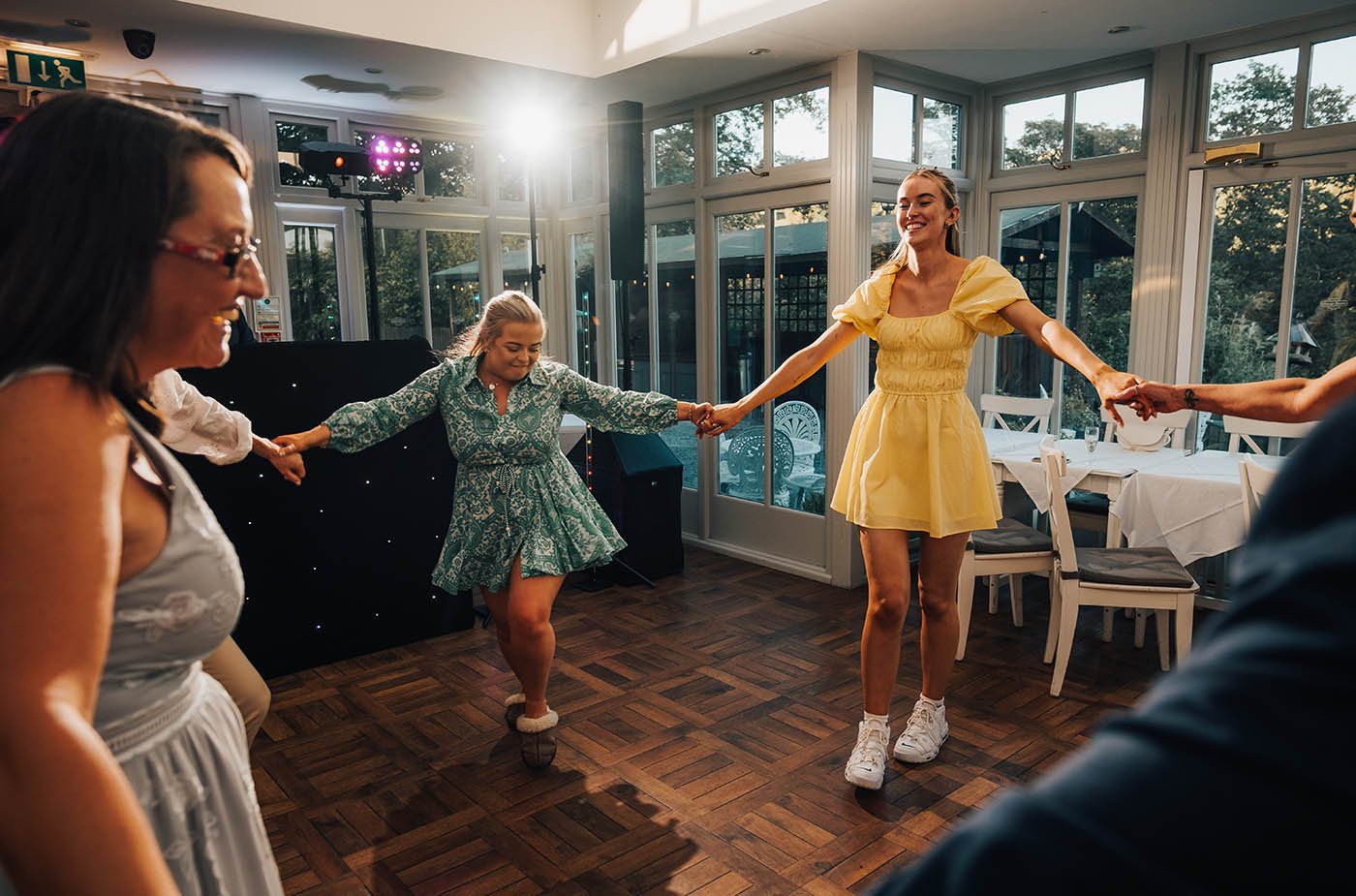 A group of wedding guests are having a great time dancing on the floor at Broadoaks Country House, a picturesque wedding venue in the Lake District. The guests are clearly enjoying themselves, with smiles on their faces and their bodies swaying to th
