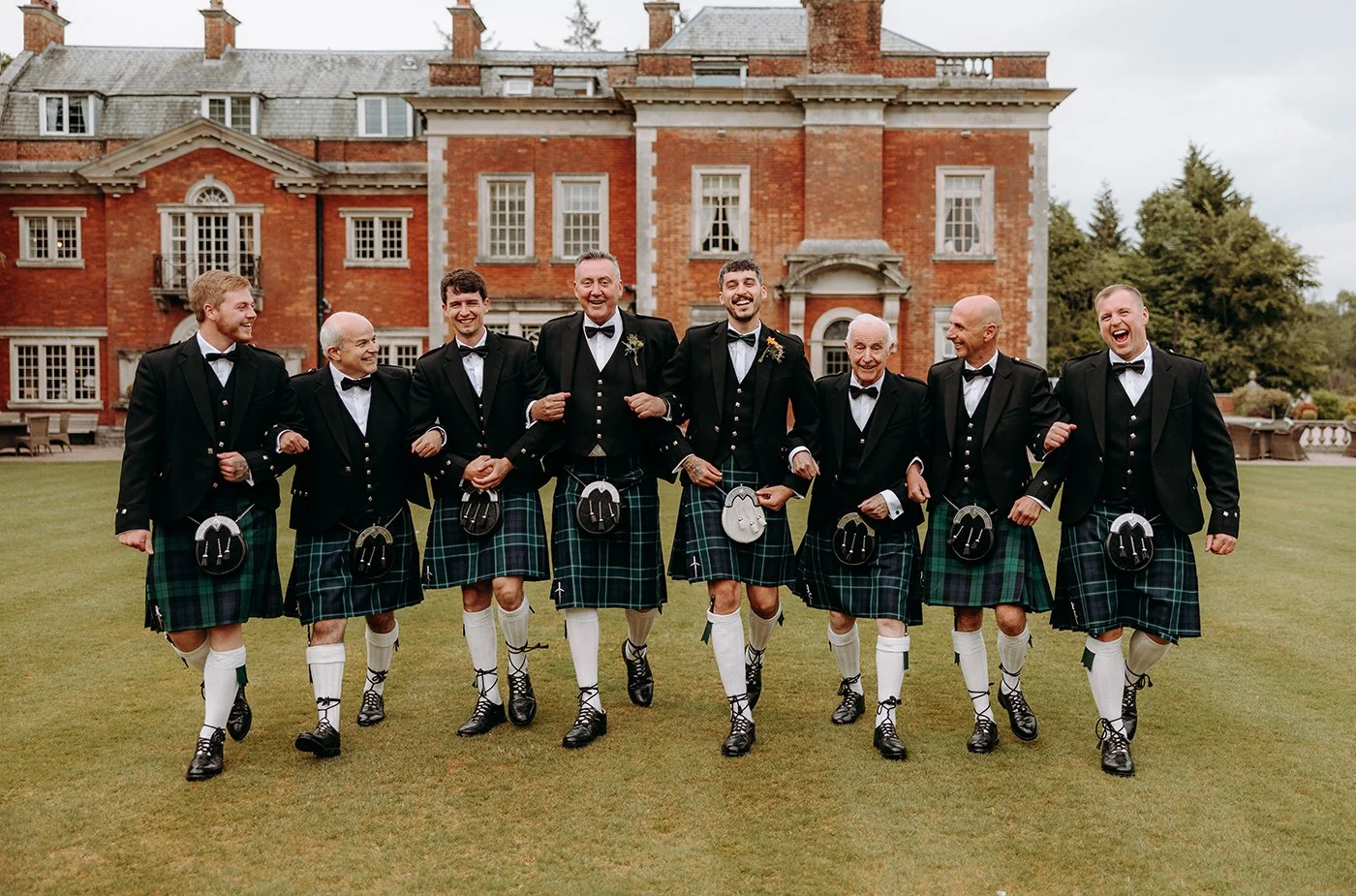 Groomsmen walking and laughing at Eaves Hall in Lancashire