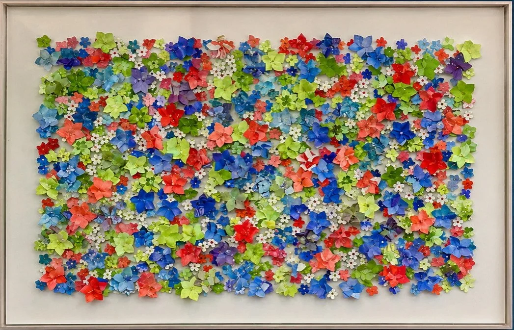 "Where the Meadow Breathes" is an immersive celebration of nature’s abundance, translated into a vibrant three-dimensional field of color, texture, and movement. Hundreds of individually hand cut flowers come together in a lively tapestry of reds, co