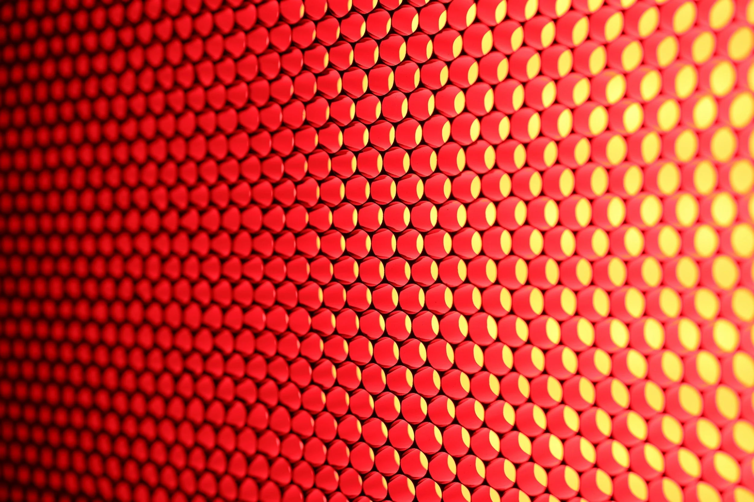 Close-up of a grid of red and yellow reflective traffic cones arranged in rows.