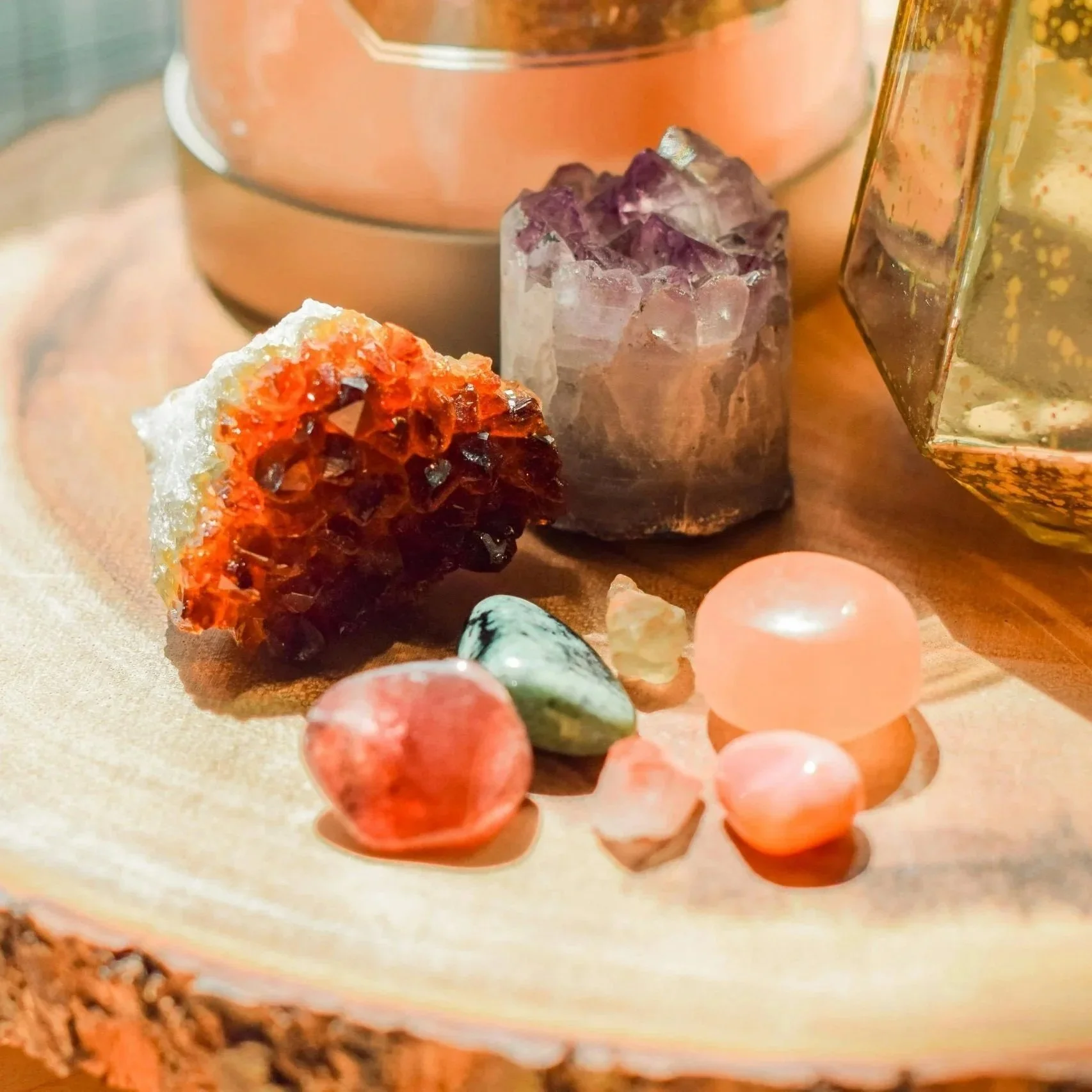Close-up of colorful mineral and gemstone specimens on a beige surface with a blurred metallic container in the background.
