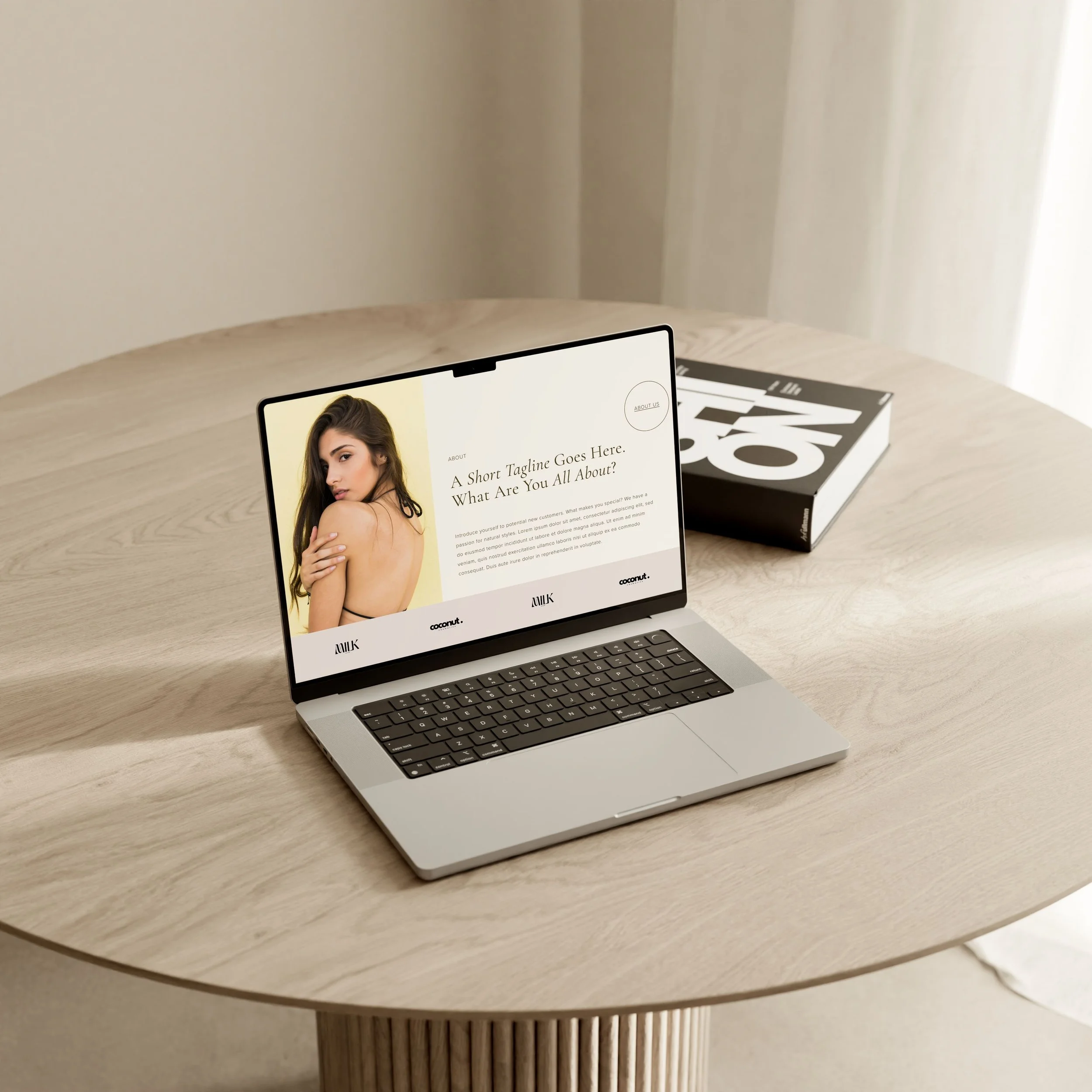 A laptop sits on a minimalist desk. The computer shows a about section of a salon website