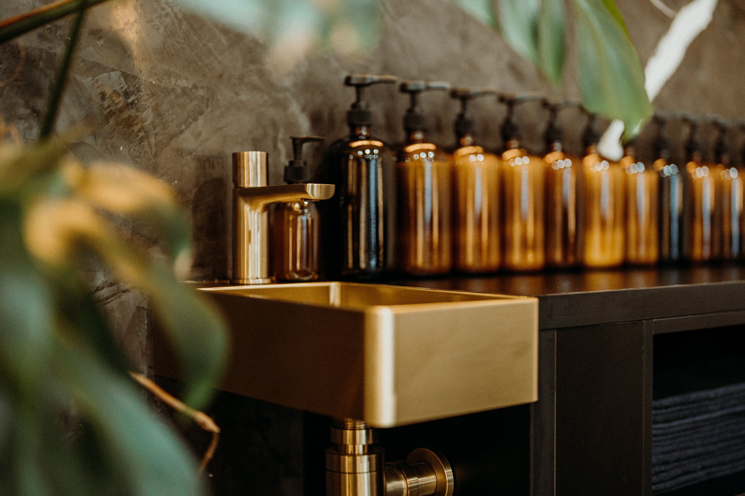 Golden sink and faucet with row of amber soap dispensers