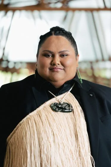 A Māori woman posing for a photo with a korowai and taonga.