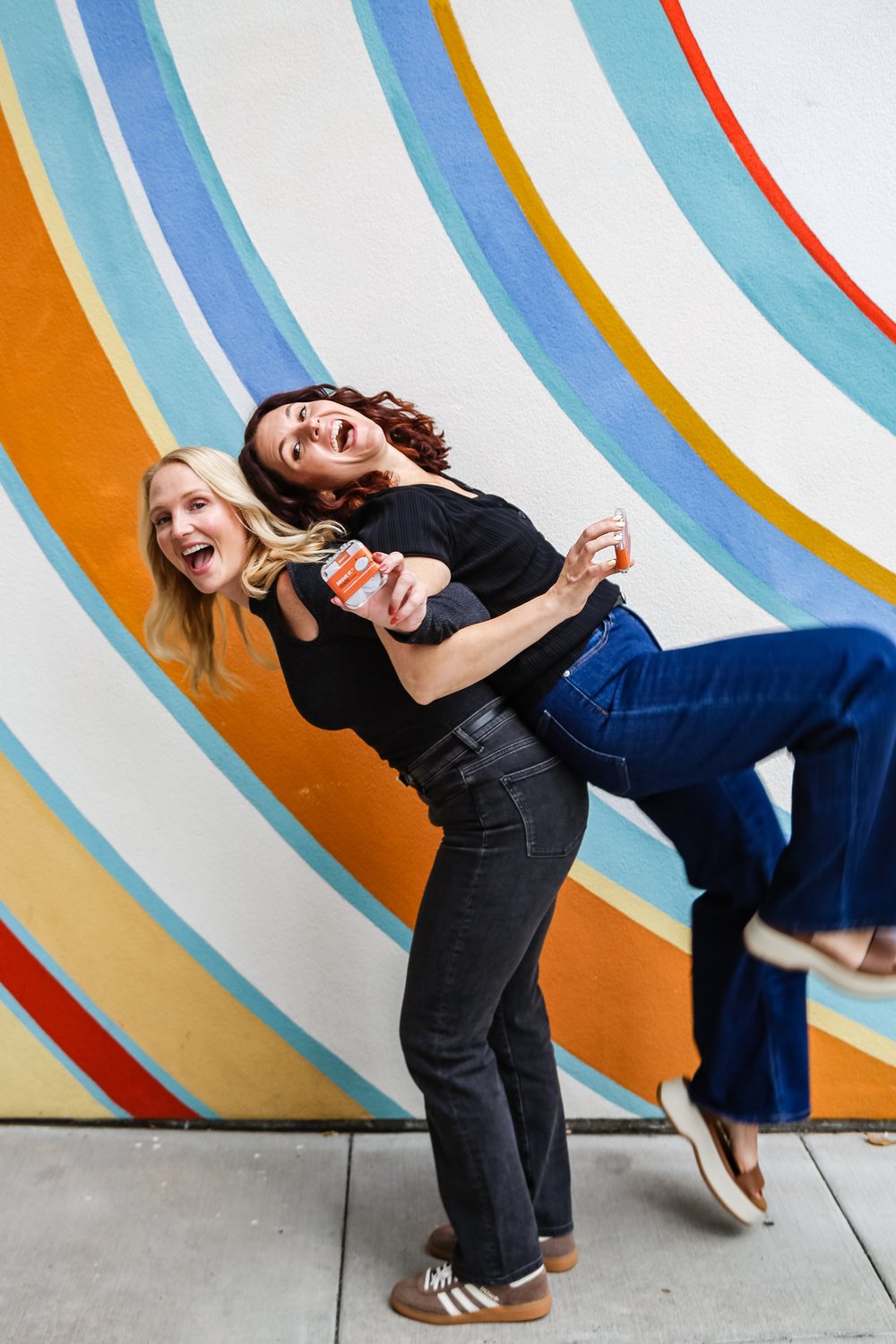 The shelpful co-founders in a playful piggyback pose