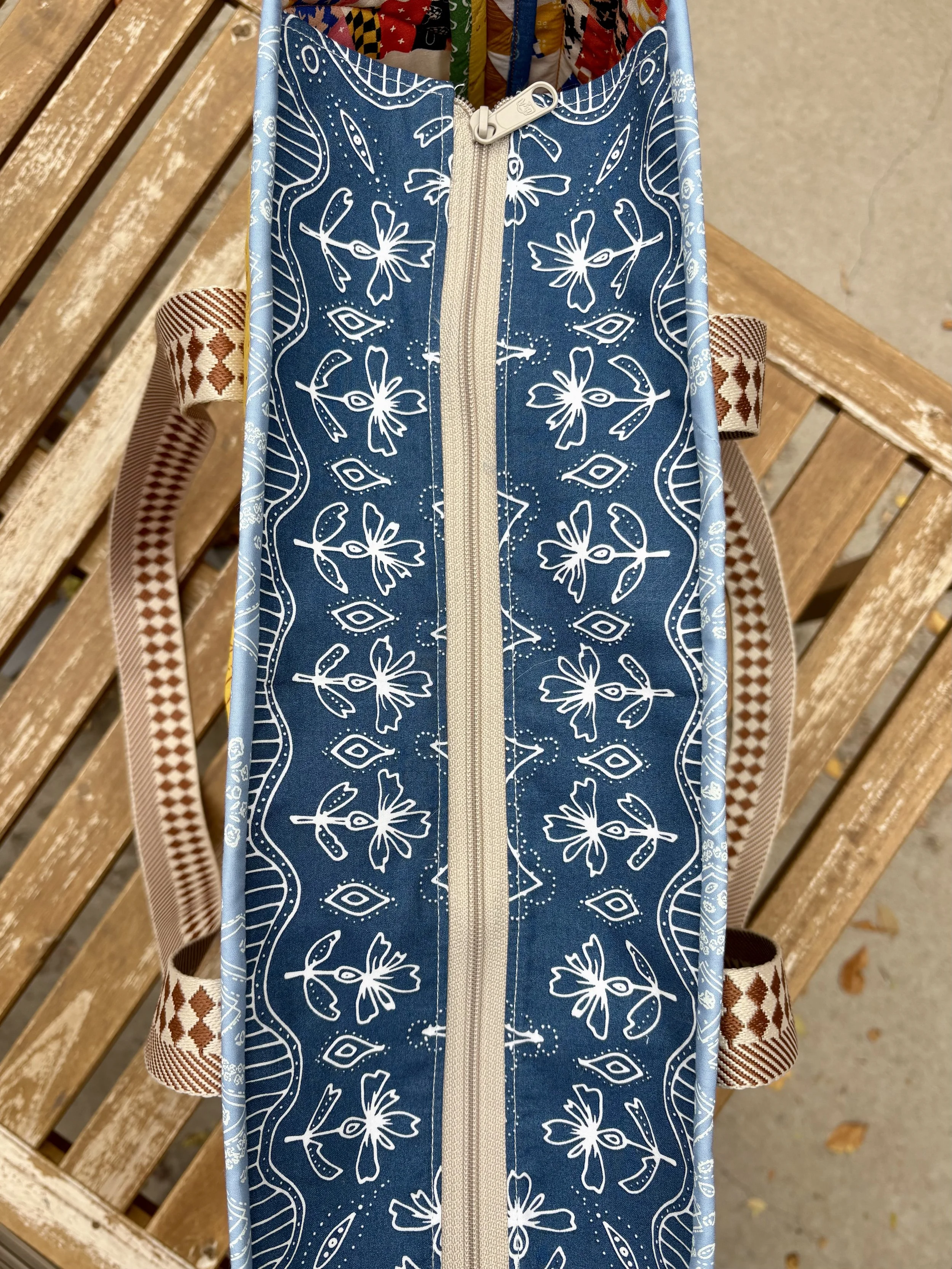 A quilted tote bag with a drop zipper insert made of blue pattern matched boho fabric