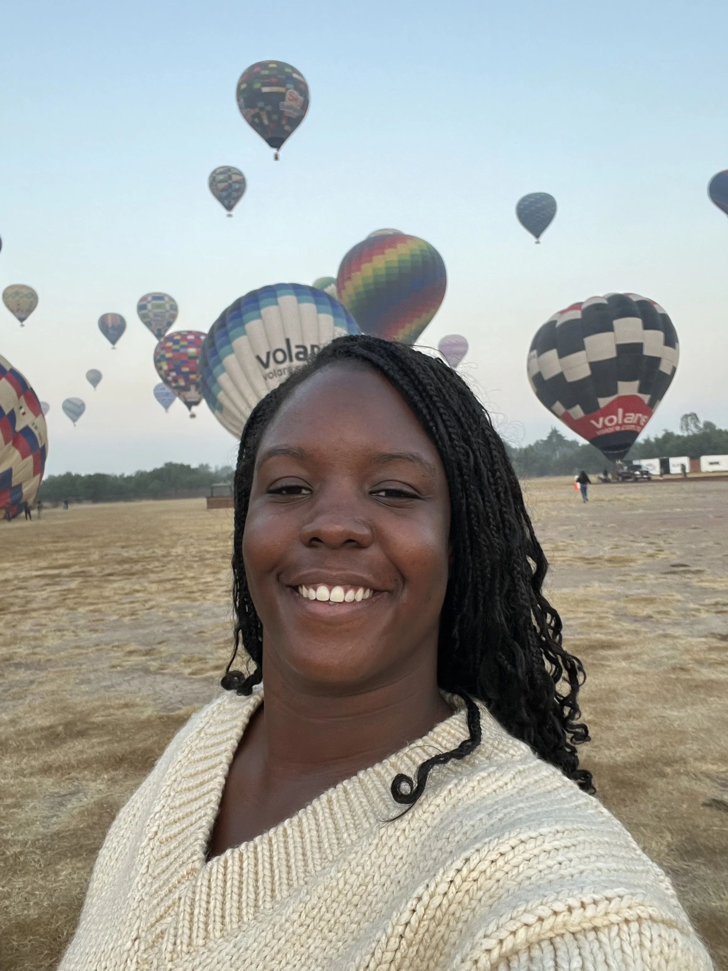 Woman smiling at camera with hot air balloons behind her