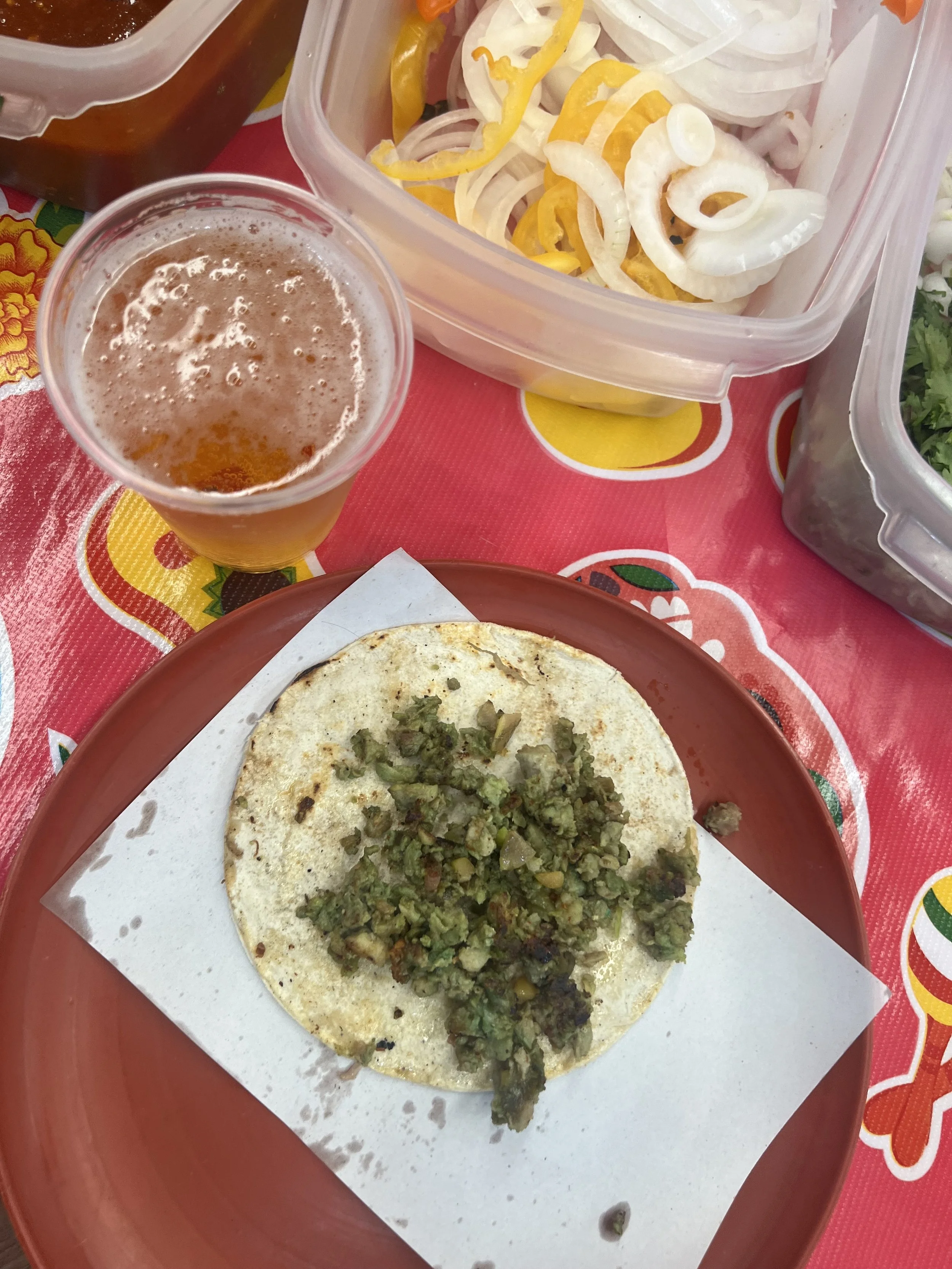 Green Chorizo Taco on a red plate with a cup of beer