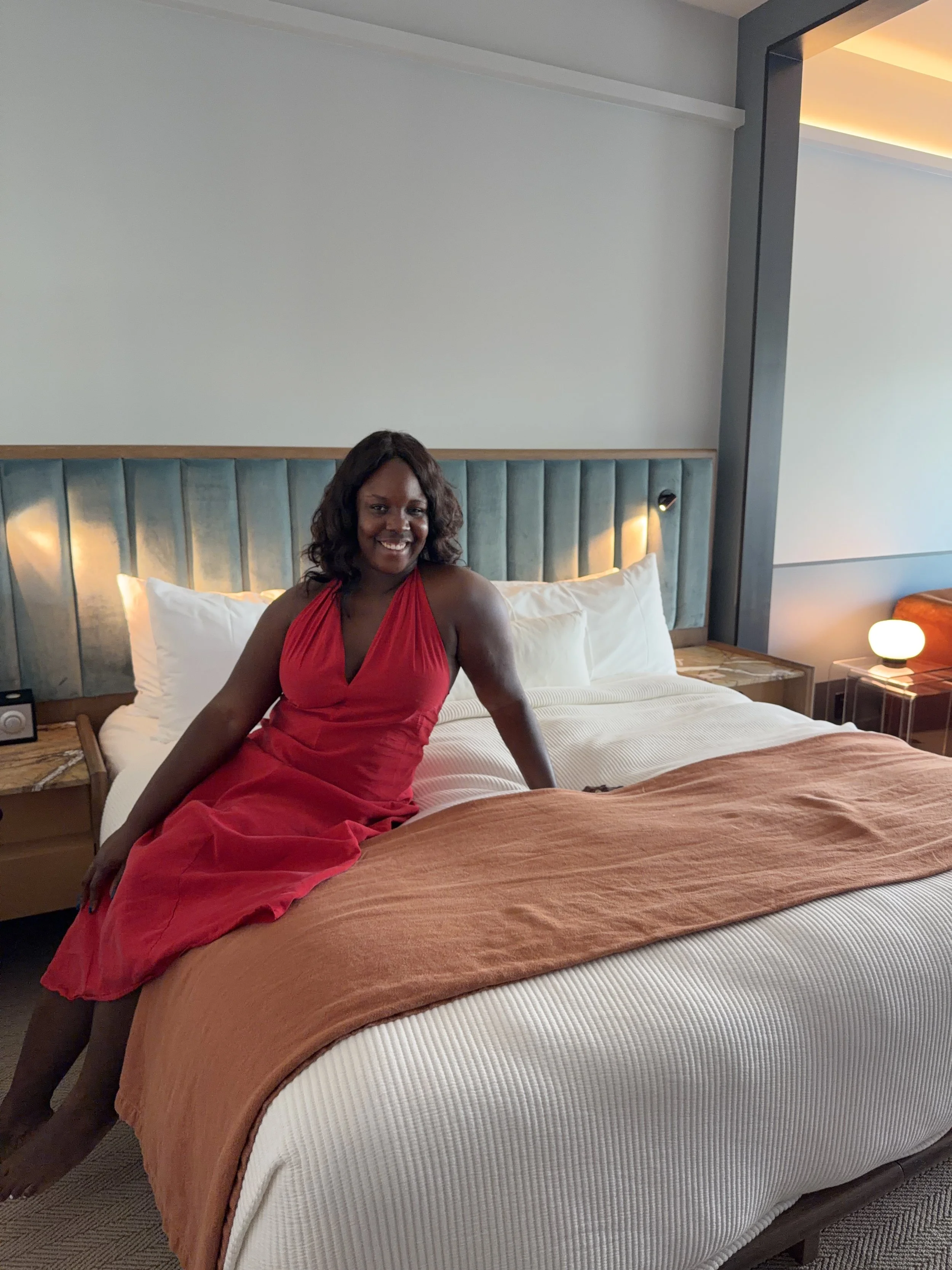 Black women in a red dress sitting on a bed at Hotel henrietta