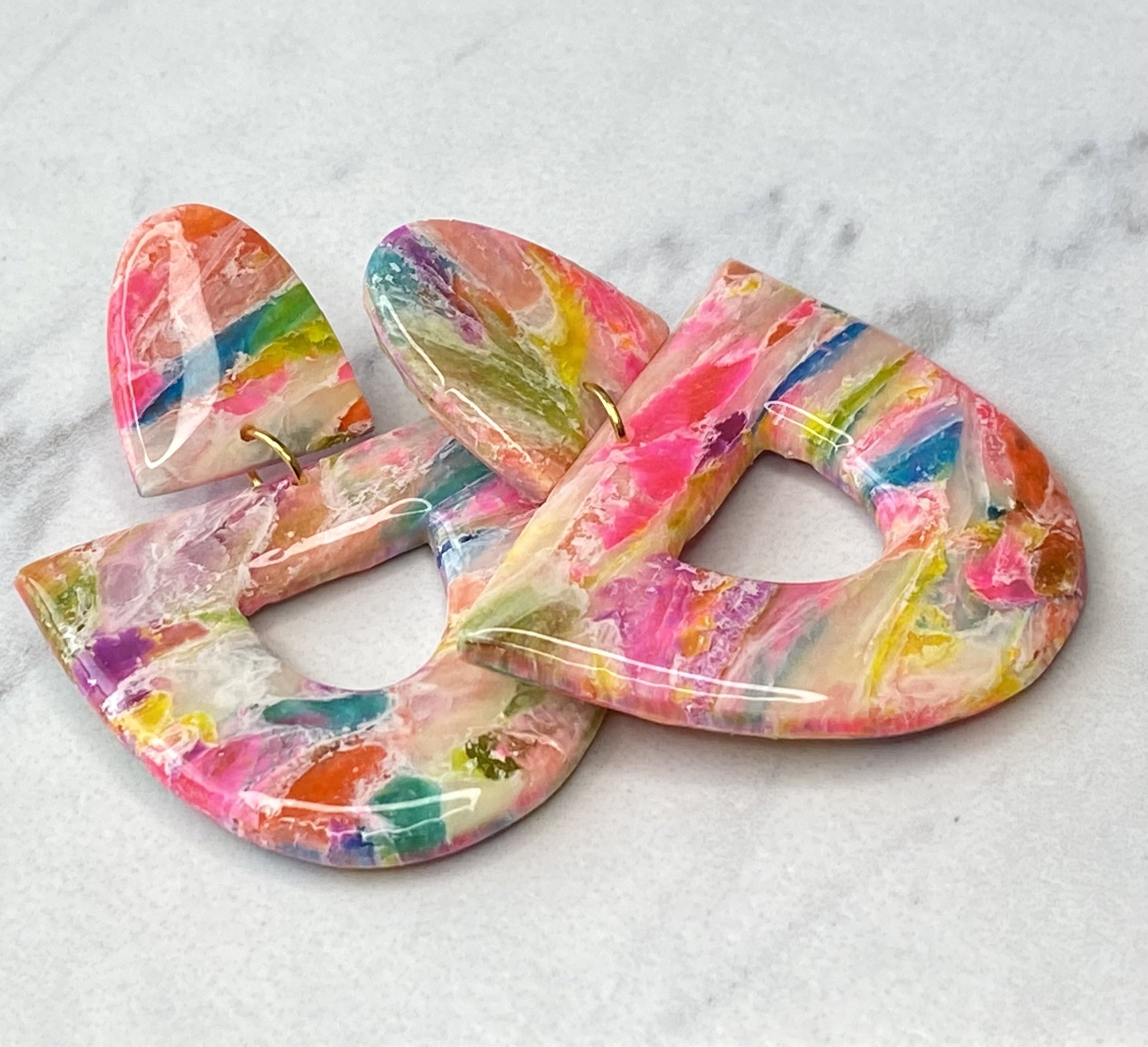 Polymer clay Colorful abstract resin earrings with marbled pattern on a light background.