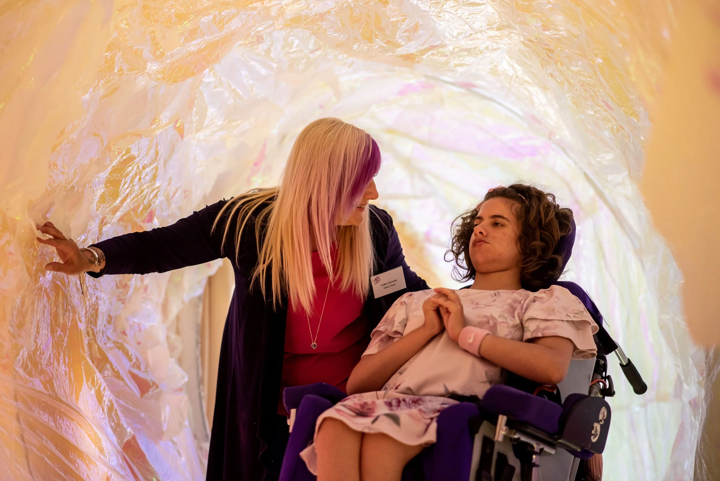 Two women, one with profound and multiple learning disabilities inside a tunel looking at each other.
