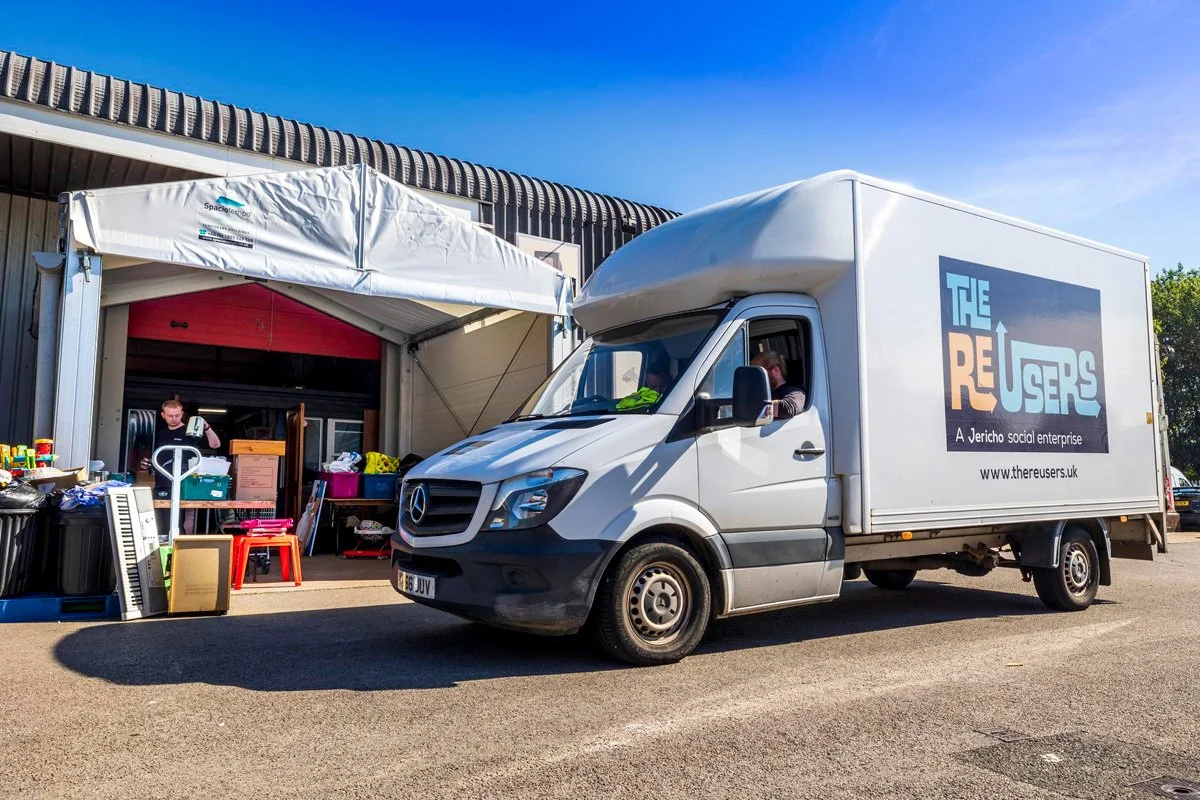 Van outside a canopy full of second hand items