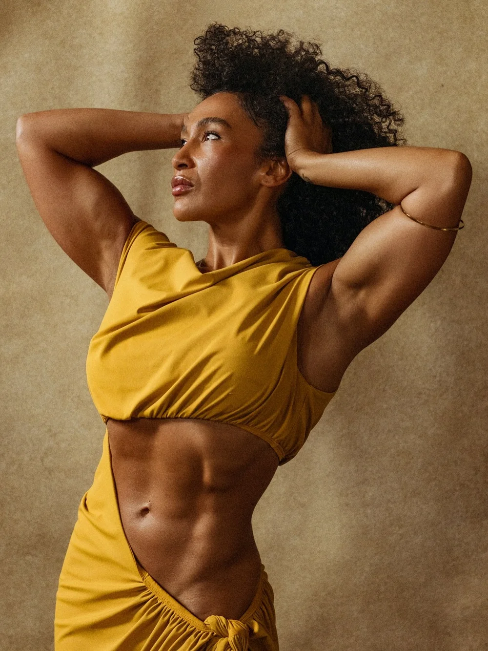 Woman in an ochre top with hands in her hair