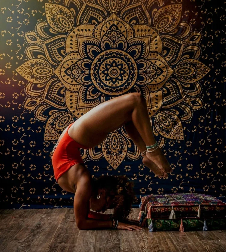 Yoga inversion before a gold mandala tapestry