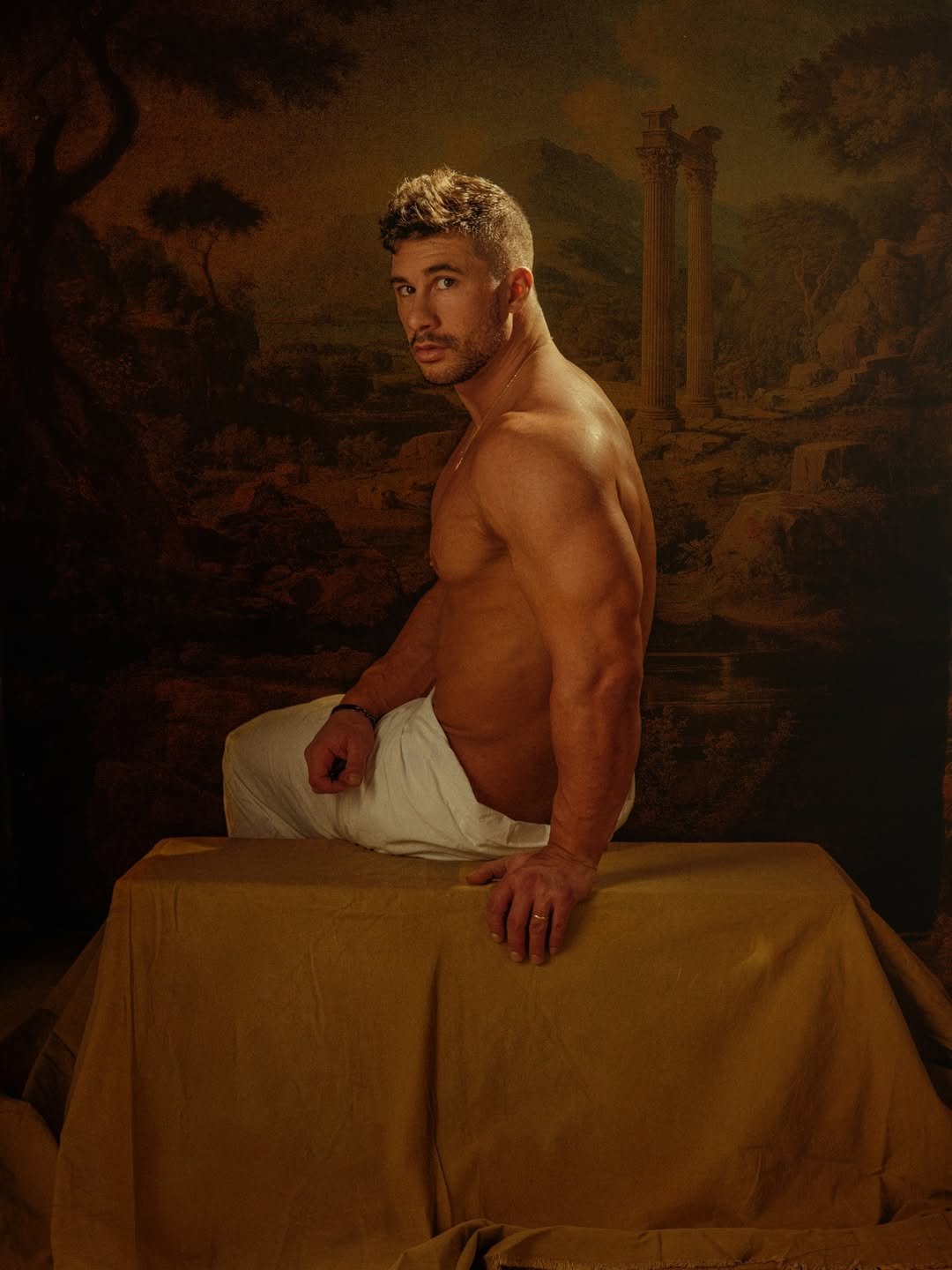 Man seated before a classical painted backdrop, fine art portrait
