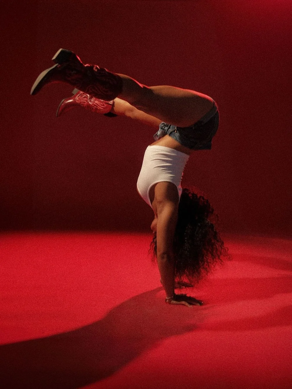 Handstand in cowboy boots in a red-lit room