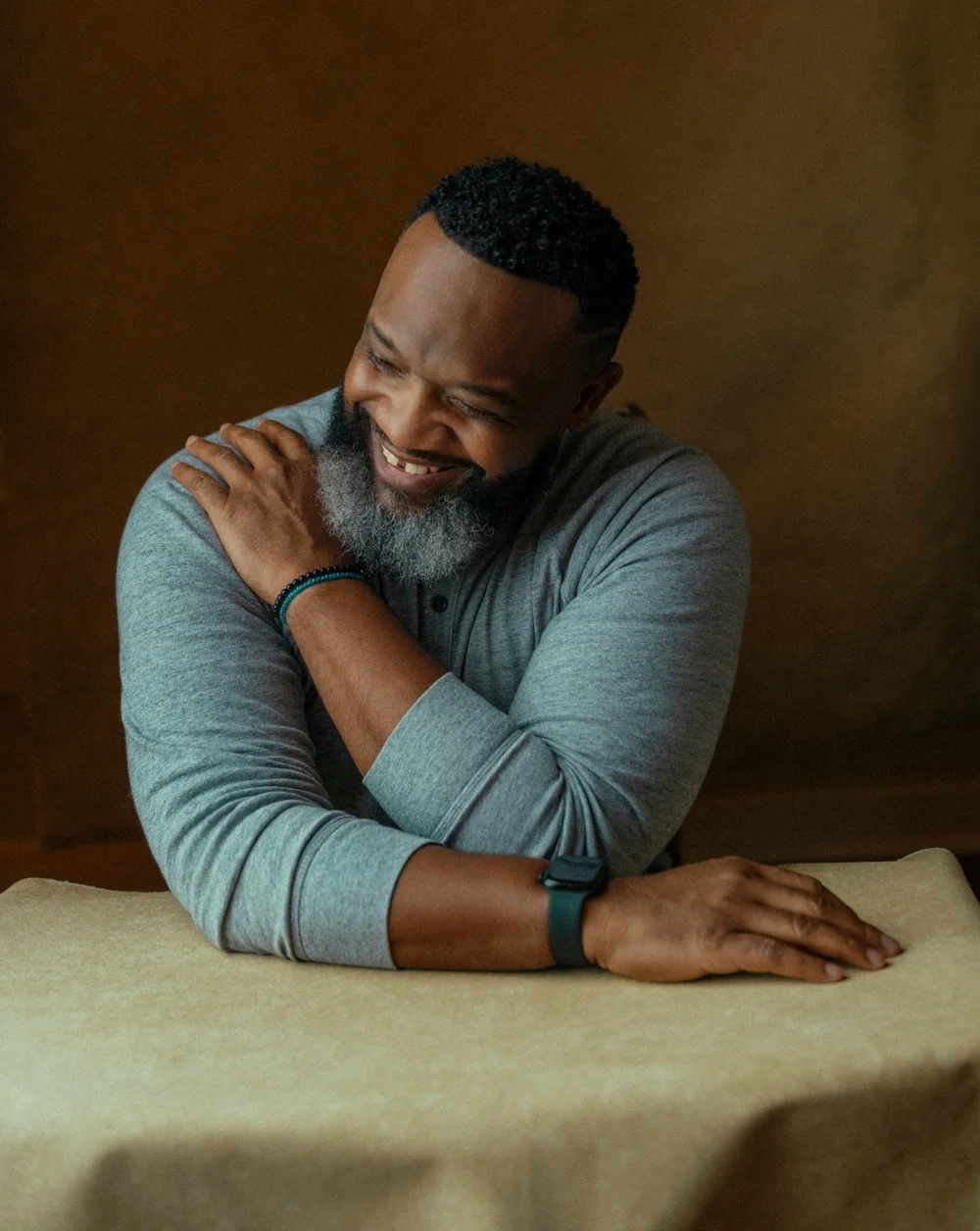 Laughing man seated at a draped table