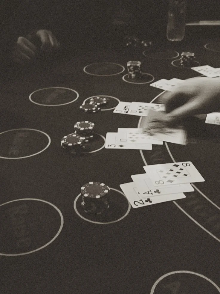 People playing blackjack at a casino table with poker chips and playing cards.