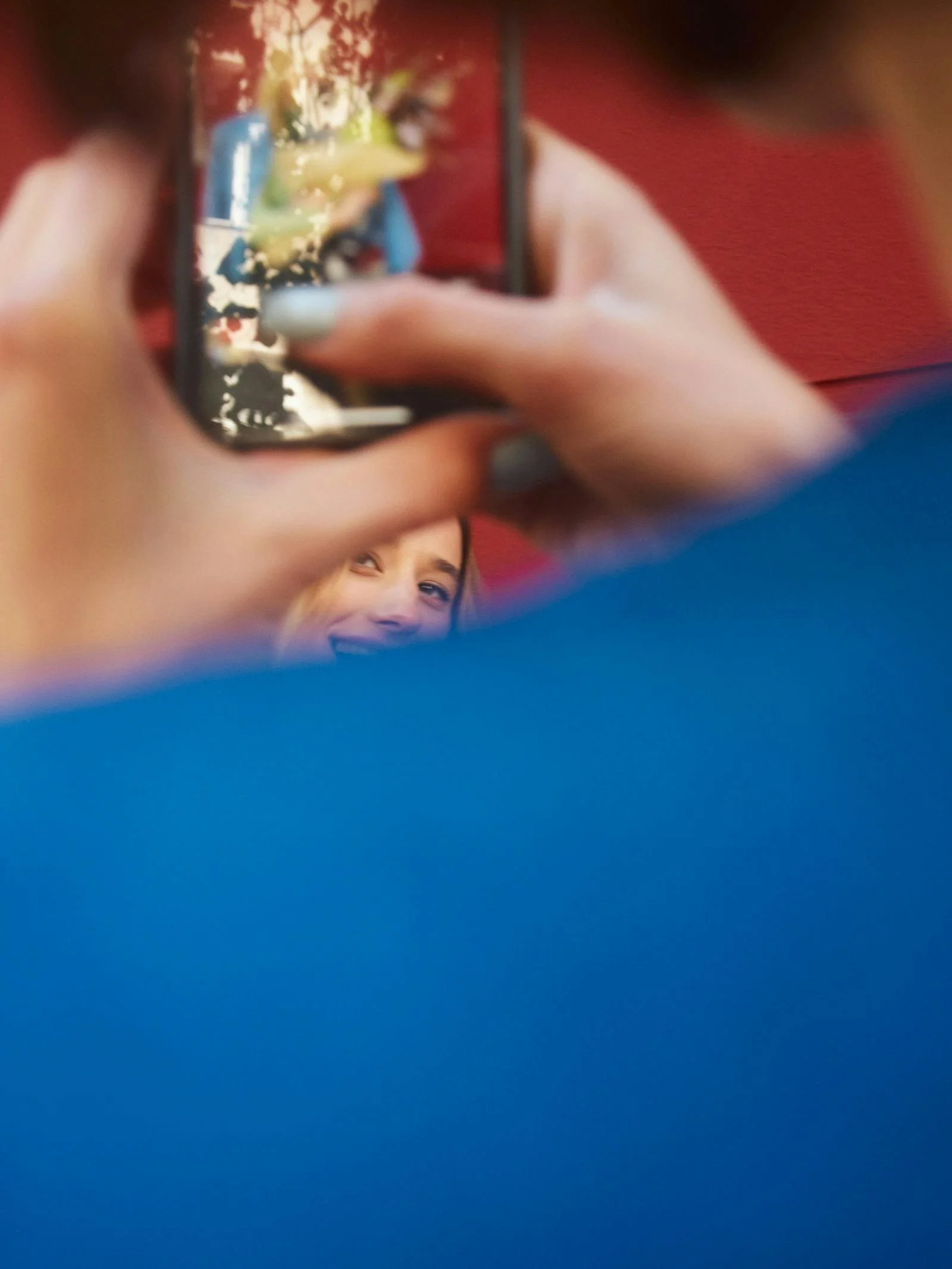 Person taking a photo of a smiling woman through a smartphone.