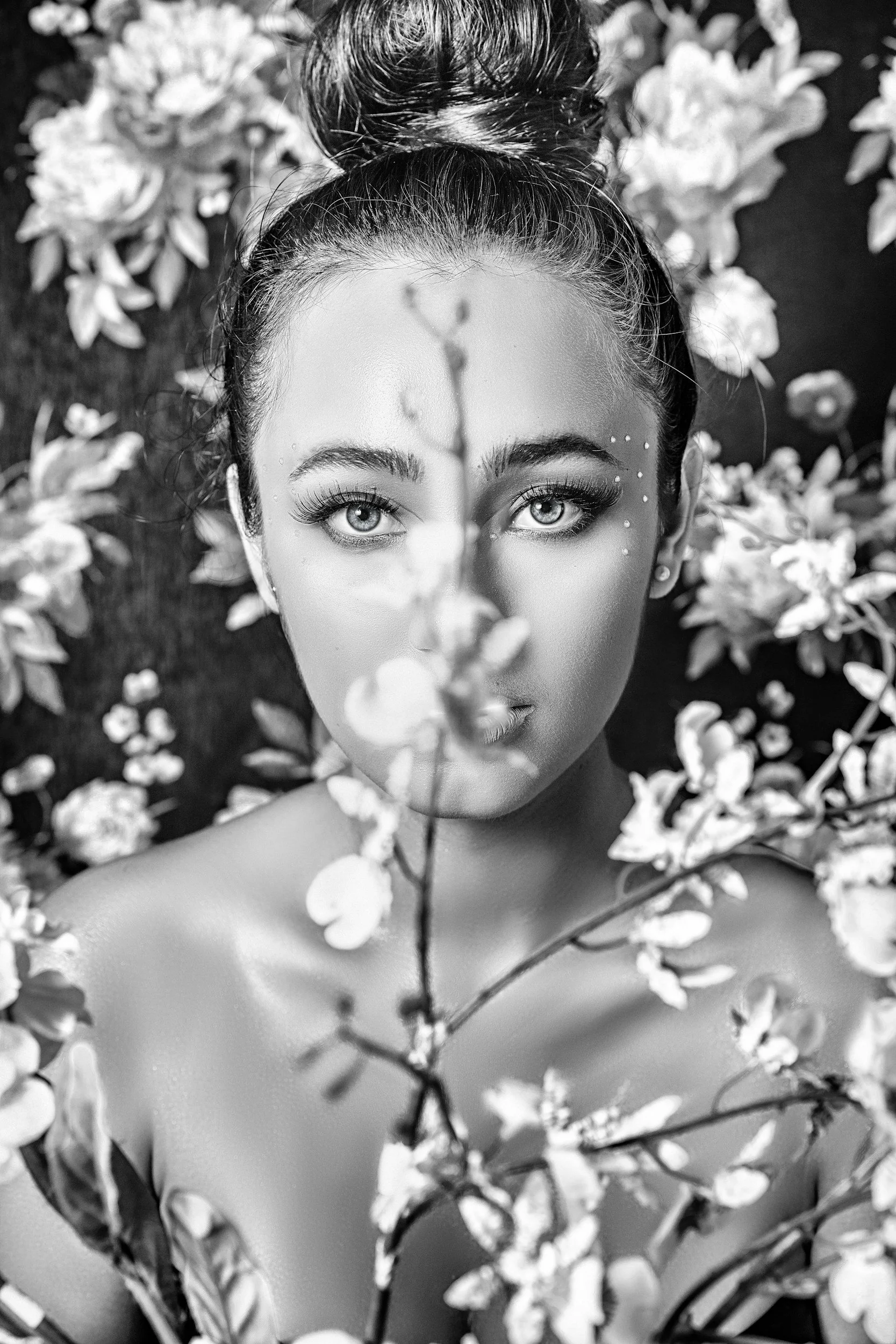 Black and white portrait of a woman with flowers, hair in a bun, white dots on her face—evoking codependent therapy Miami themes.