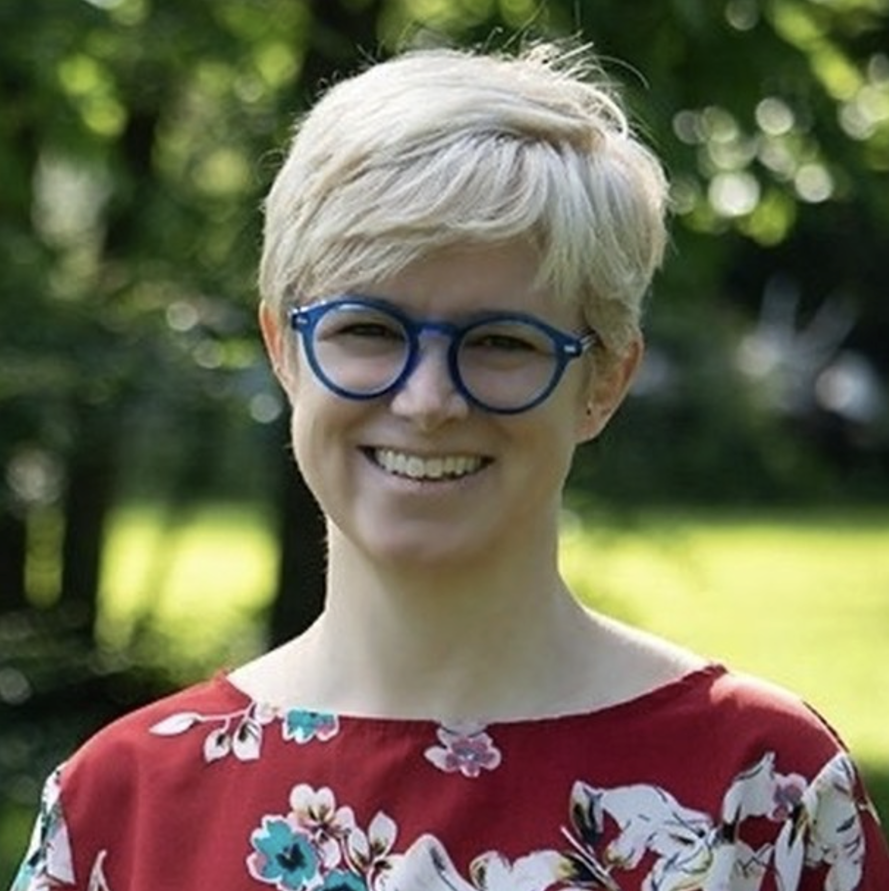 Website designer Diane outdoors smiling at camera with pink and yellow striped sweater