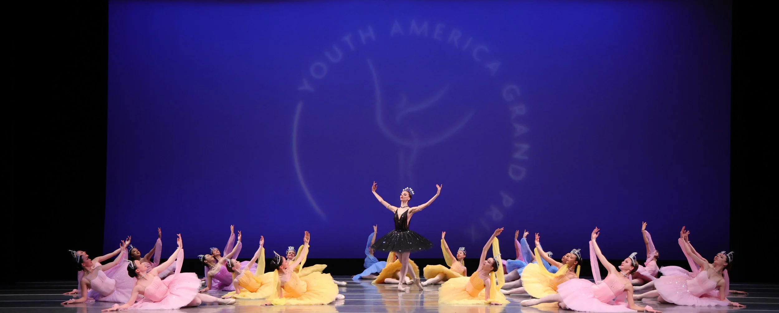 Ballet dancers performing on stage with a large blue screen background showing the Southern California Dance logo.