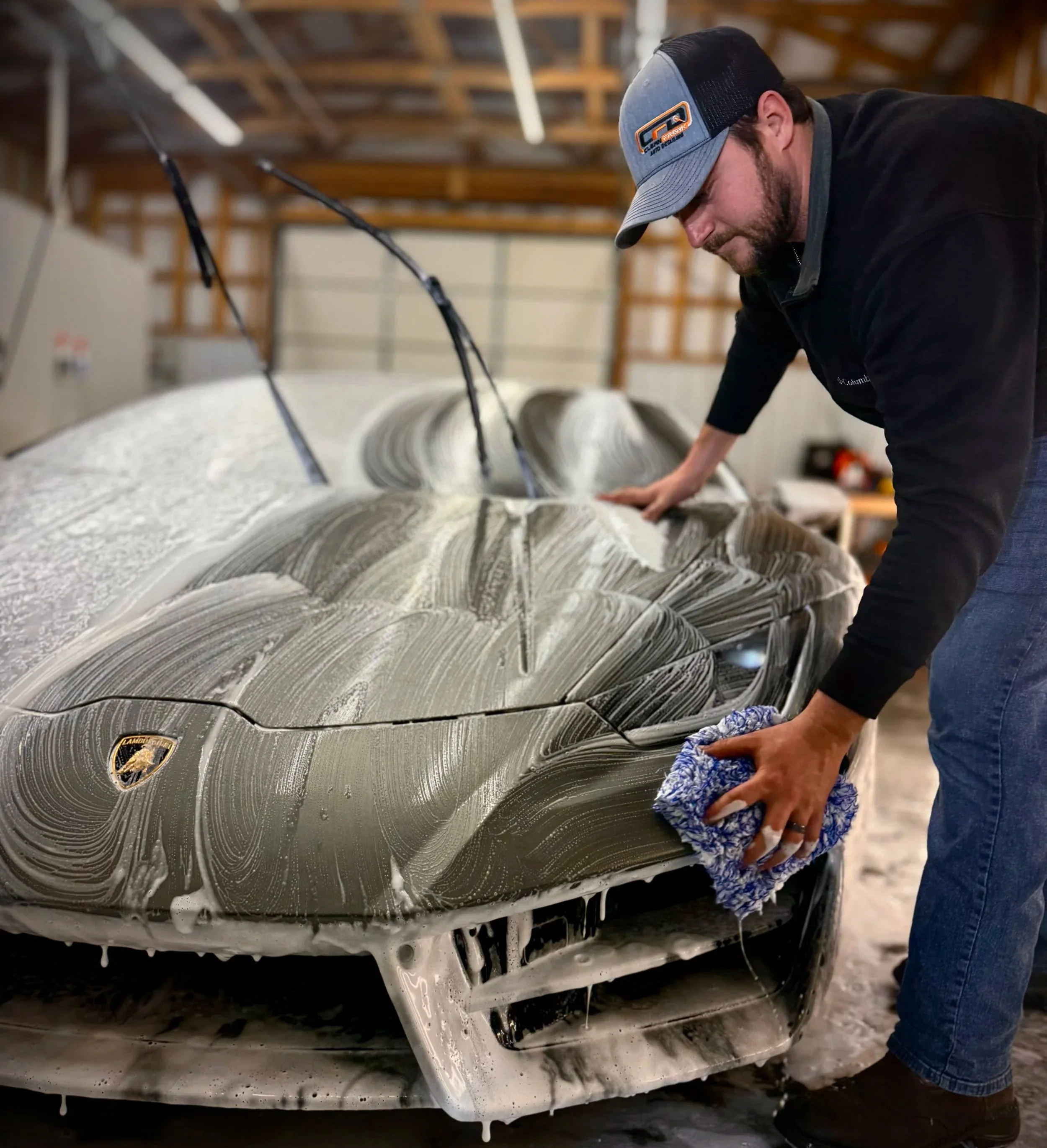 Professional auto detailing on a luxury vehicle with foam wash and hand cleaning