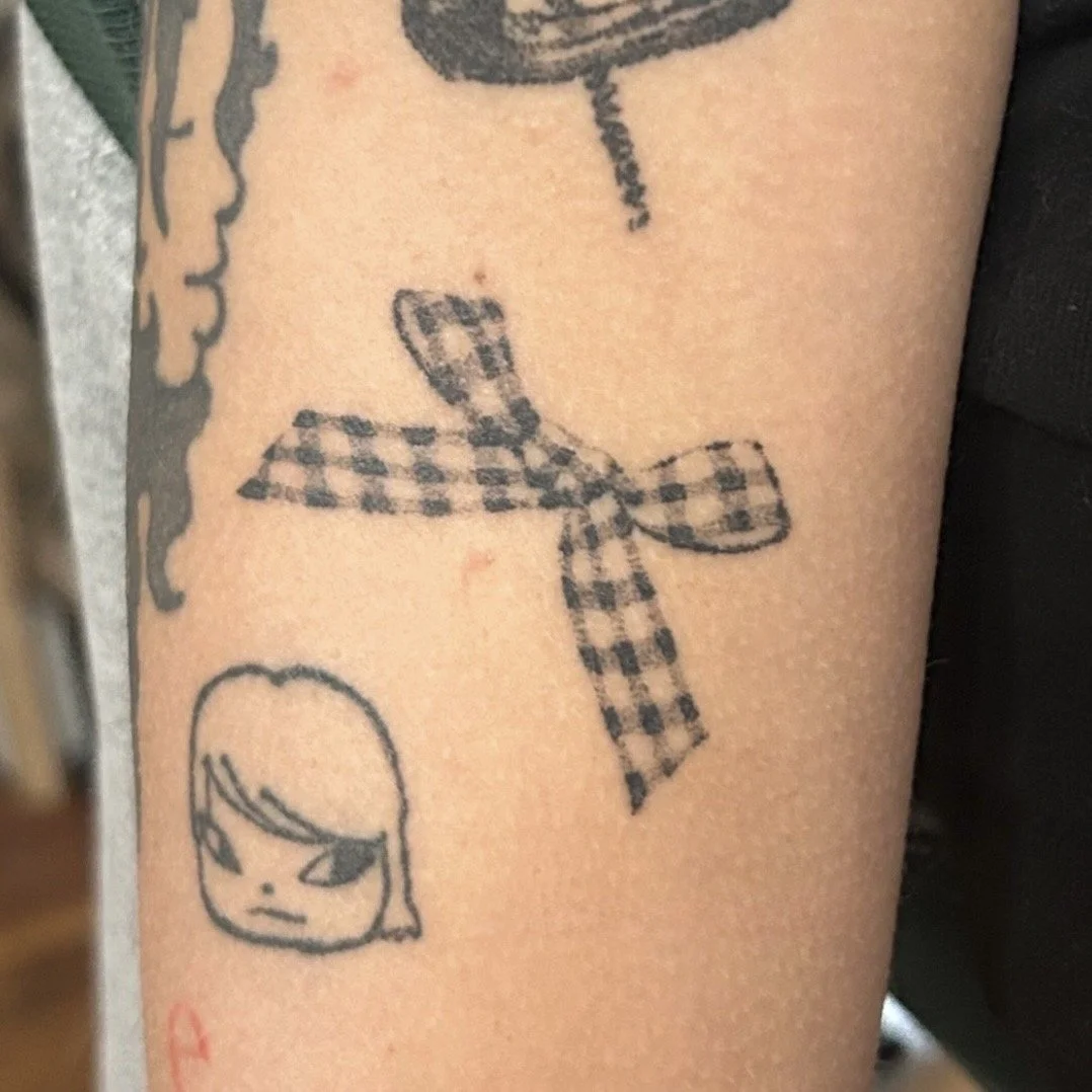 Tattoo of a gingham bow on the upper arm