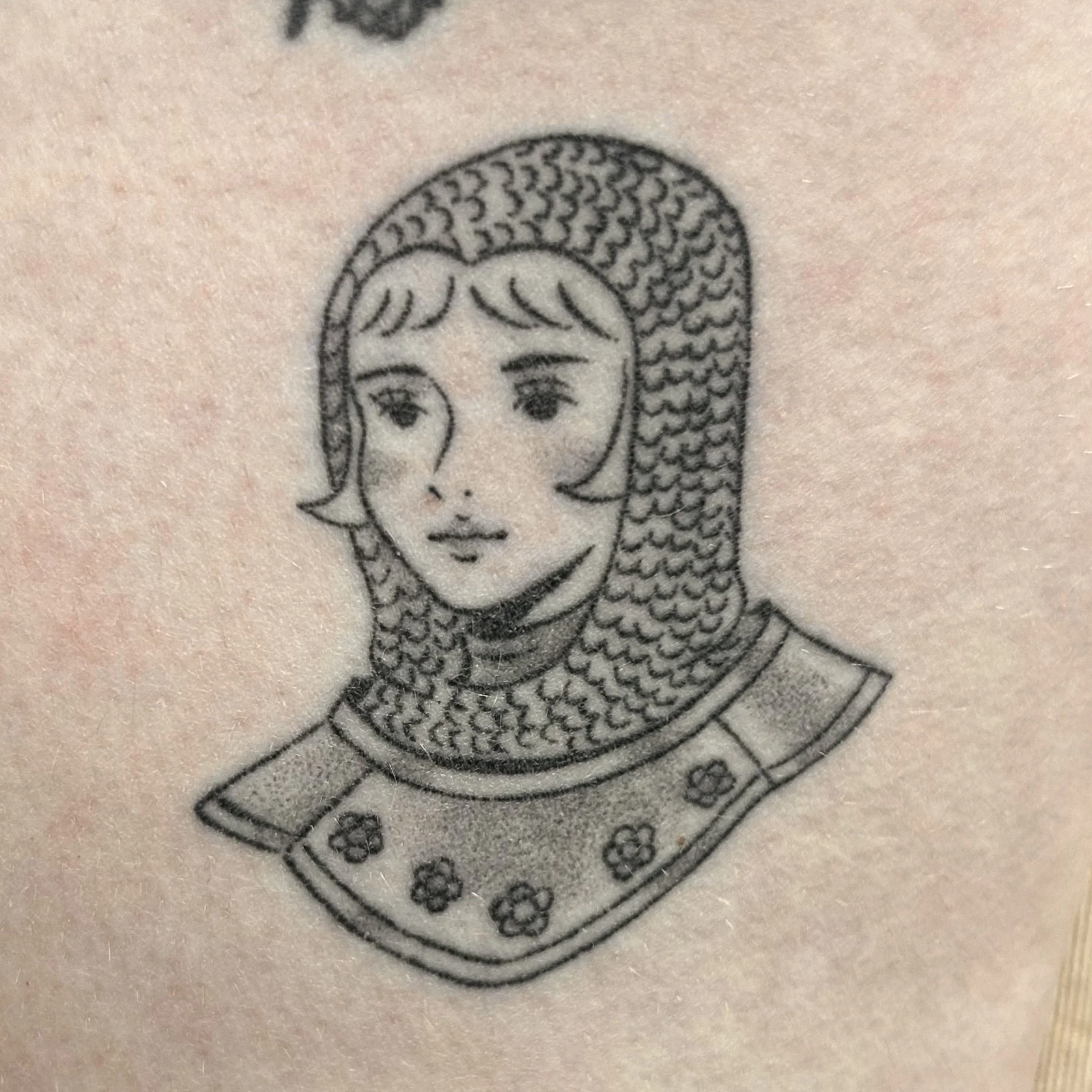 Tattoo of a female knight wearing a chainmail coif and armor 