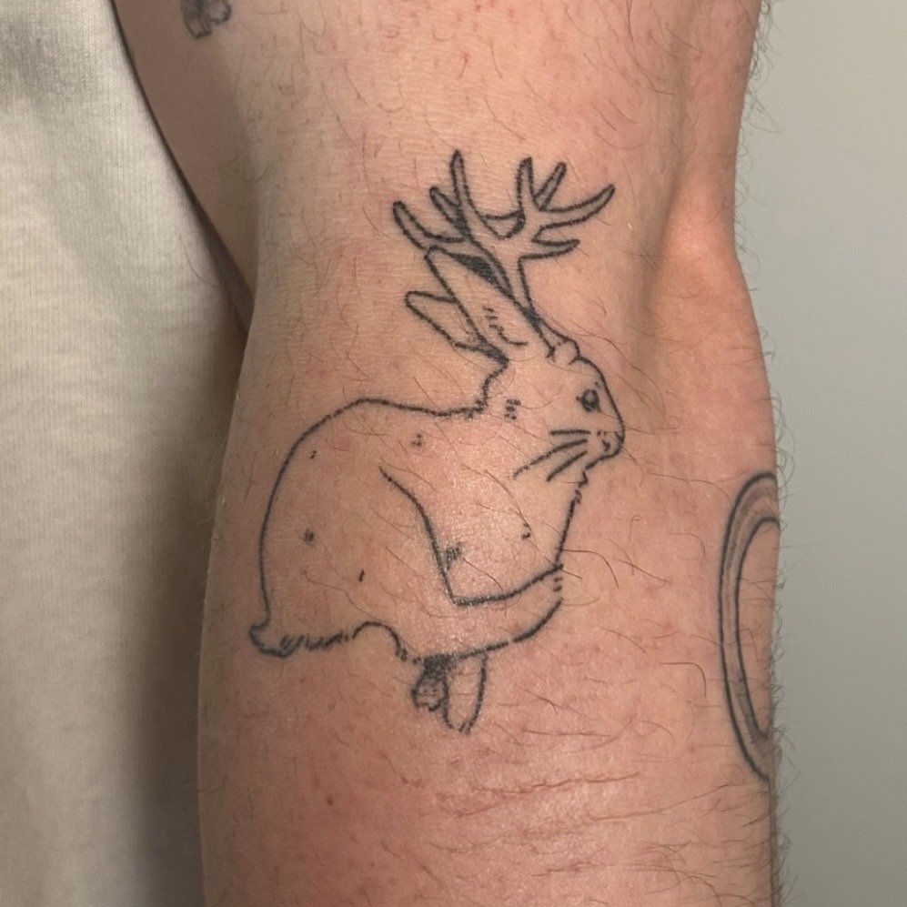 A tattoo of a rabbit with antlers on the arm