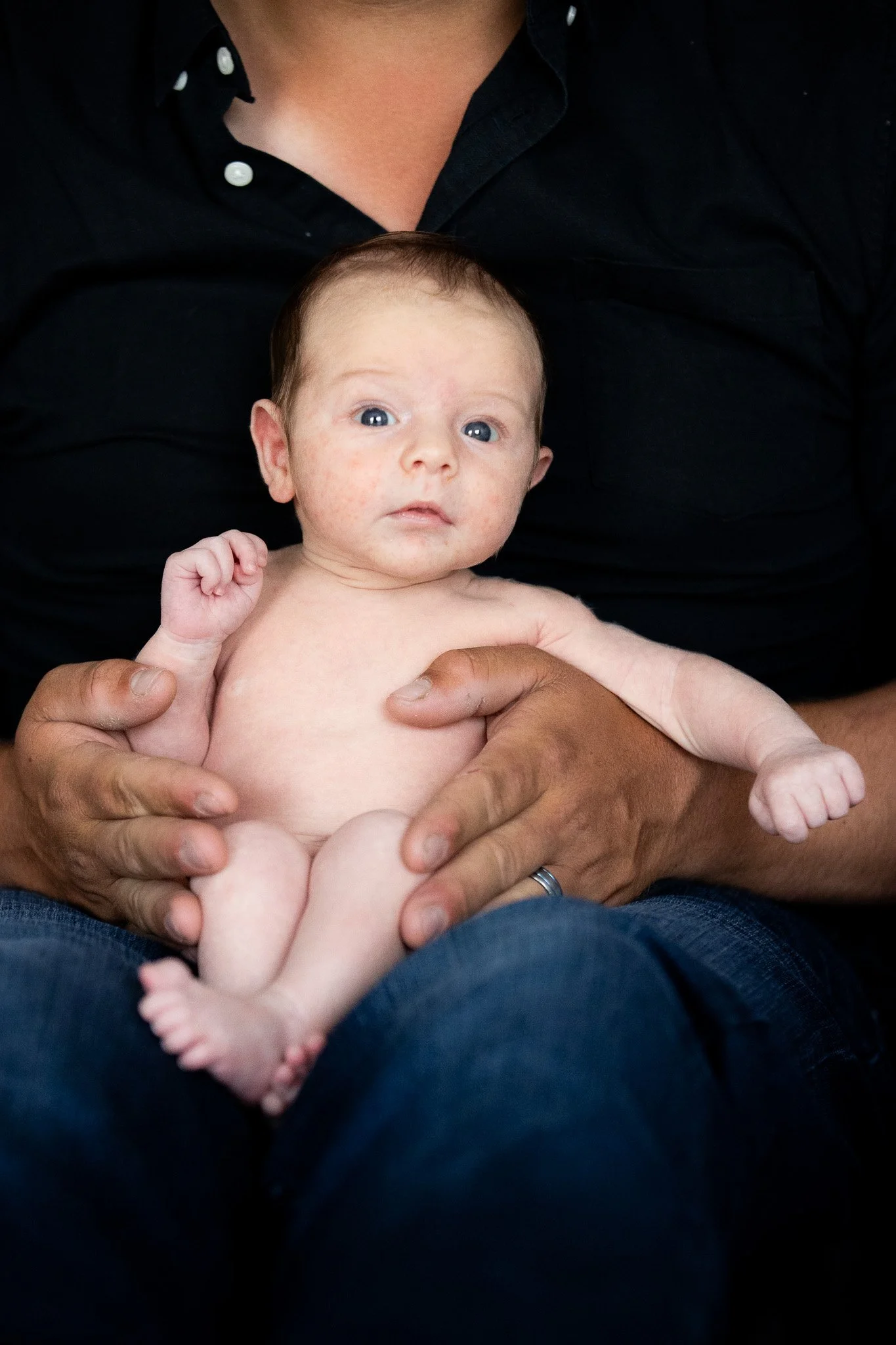 Snuggle Pix Photography | A newborn baby is photographed sitting on his Dad's lap during a photo session at home | Noosa | Brisbane | Sunshine Coast.jpg