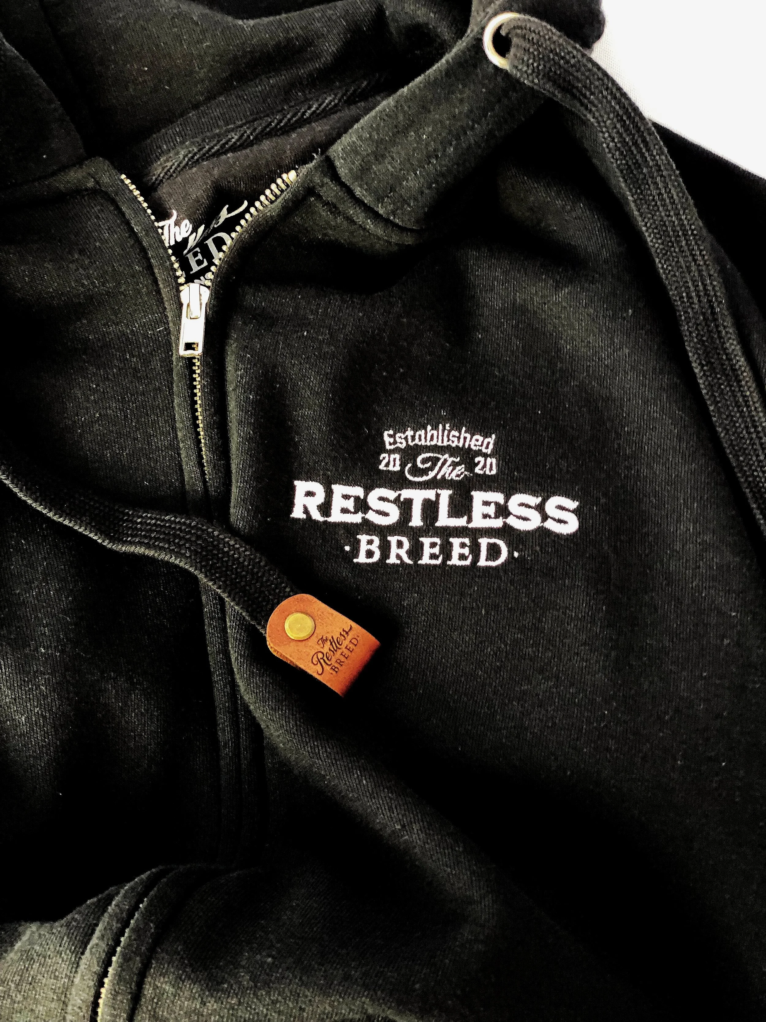 close up of restless breed embroided block logo with white thread