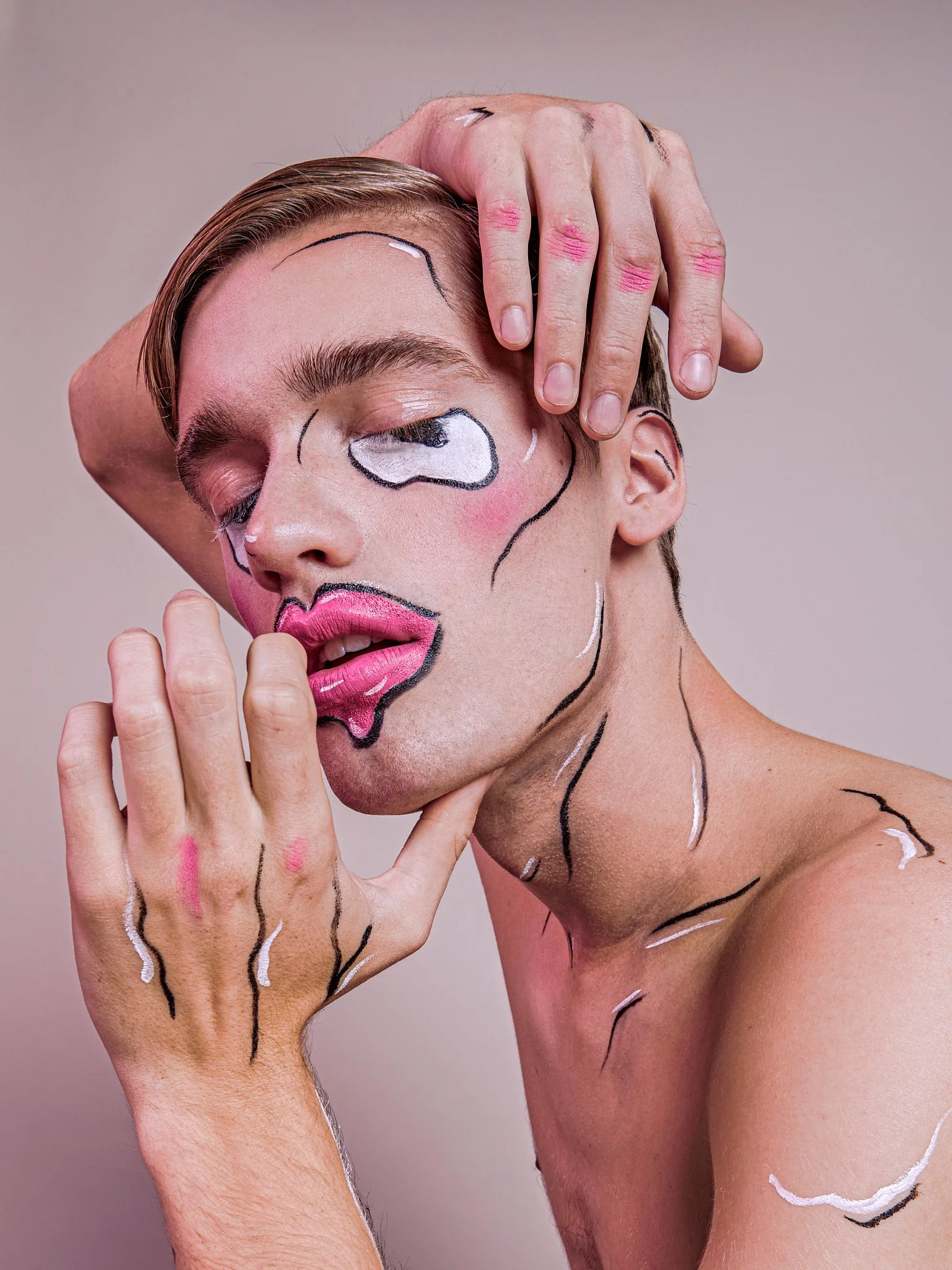 A person with pop art-style makeup resembling comic book art, with bold lines and pink lips, posing with their hand on their face and their eyes closed.
