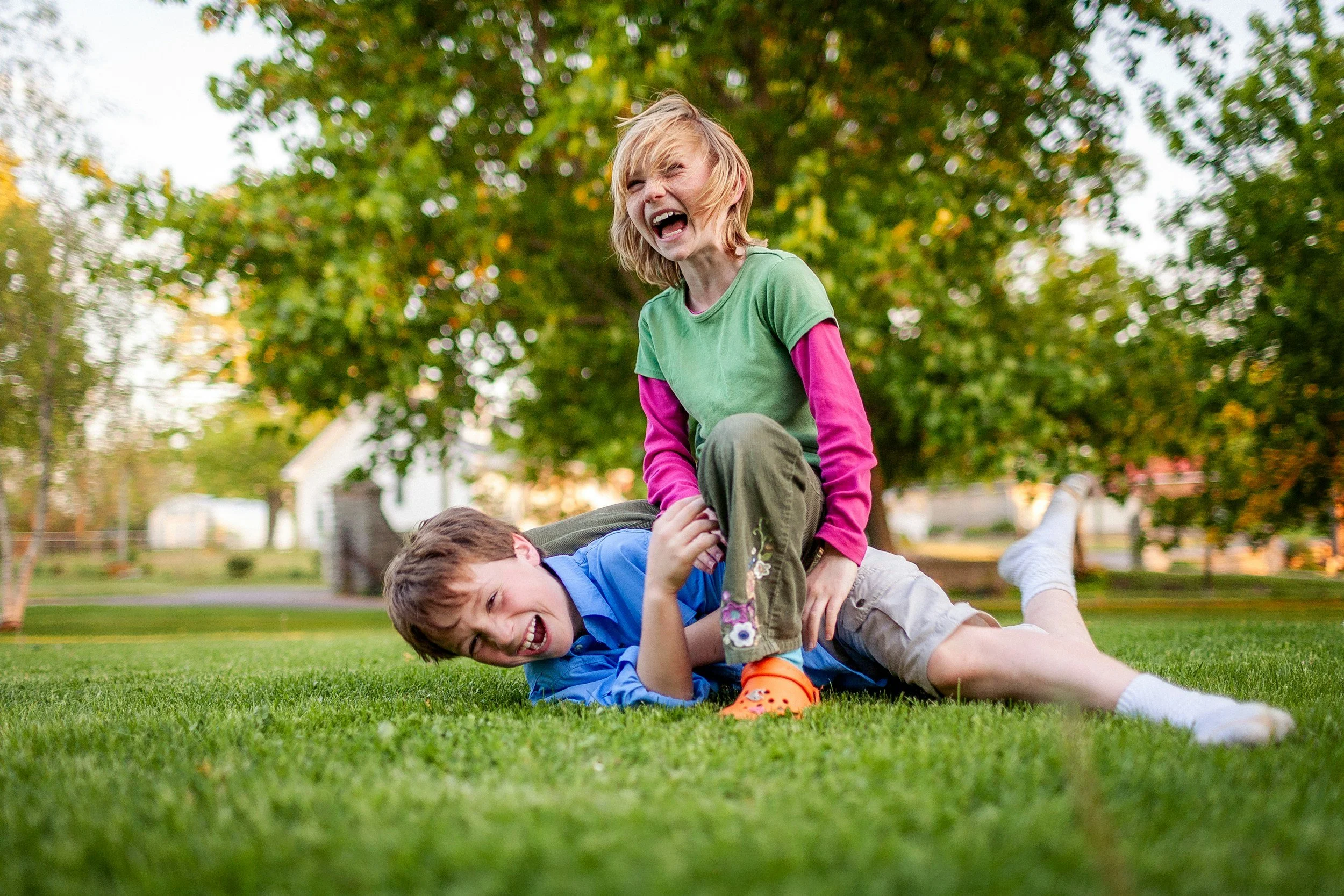 two kids laughing while playing in the yard