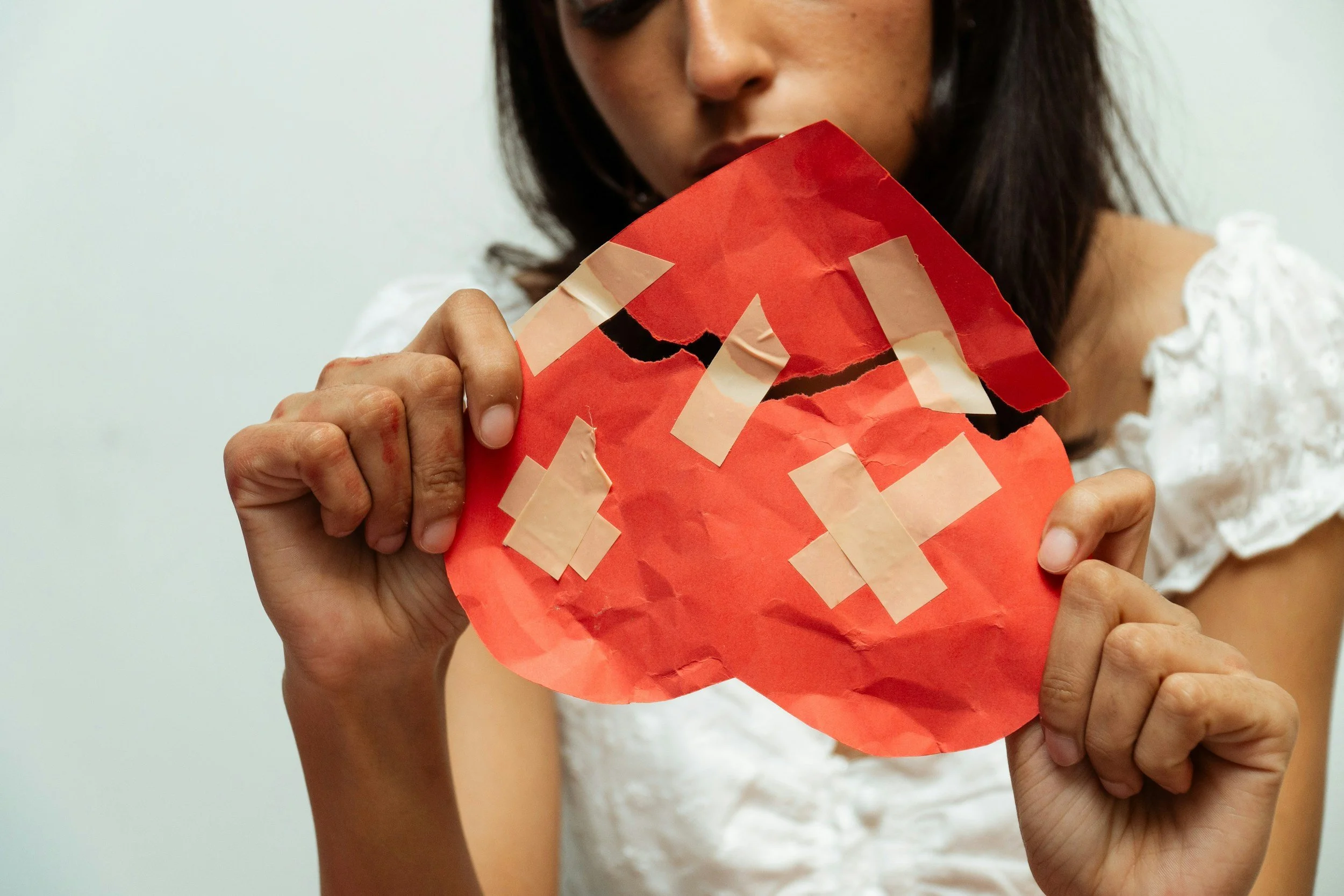 a person holding a torn heart paper