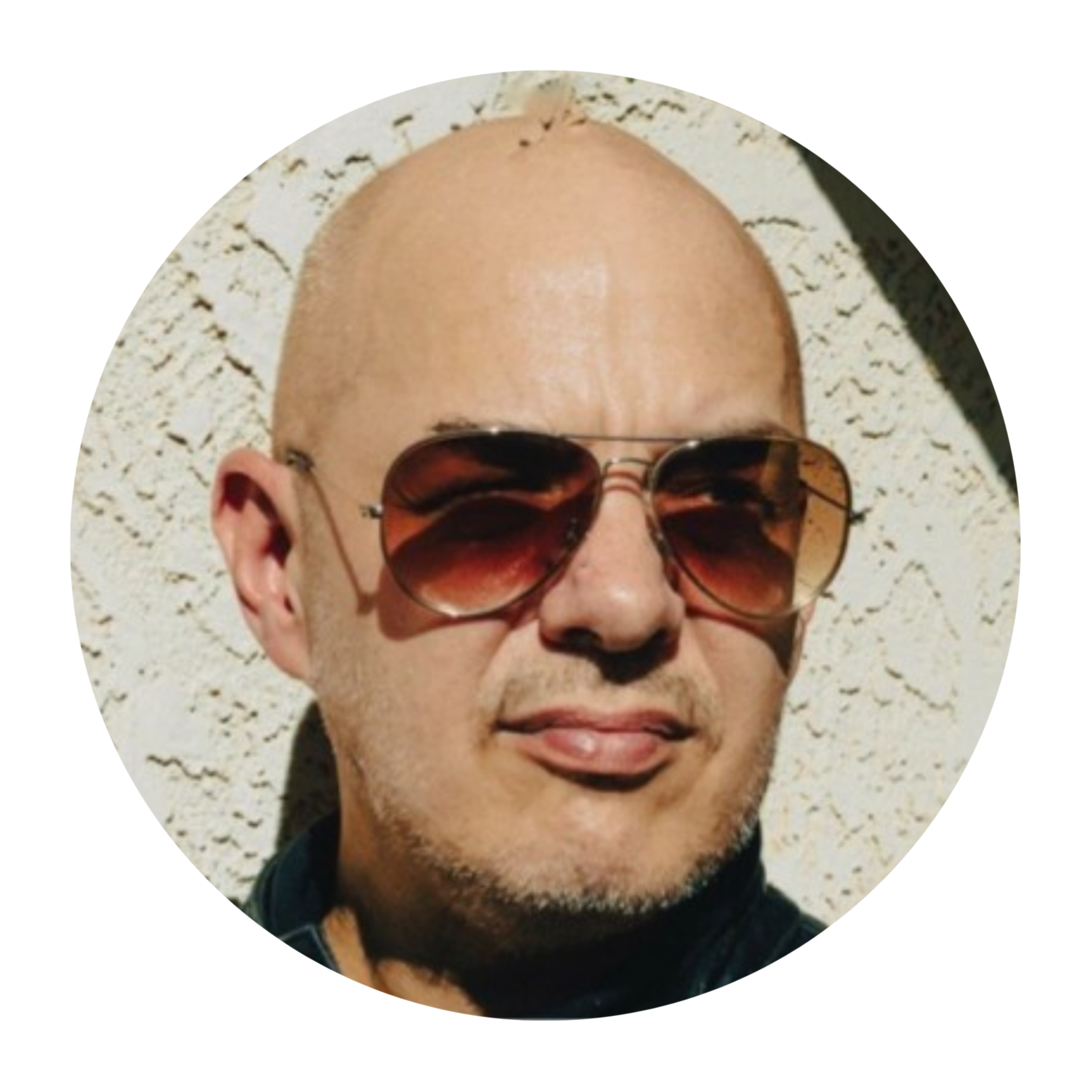 Alex Roy, LinkedIn headshot with a shaved head and sunglasses smiling, with a granite countertop in the background.