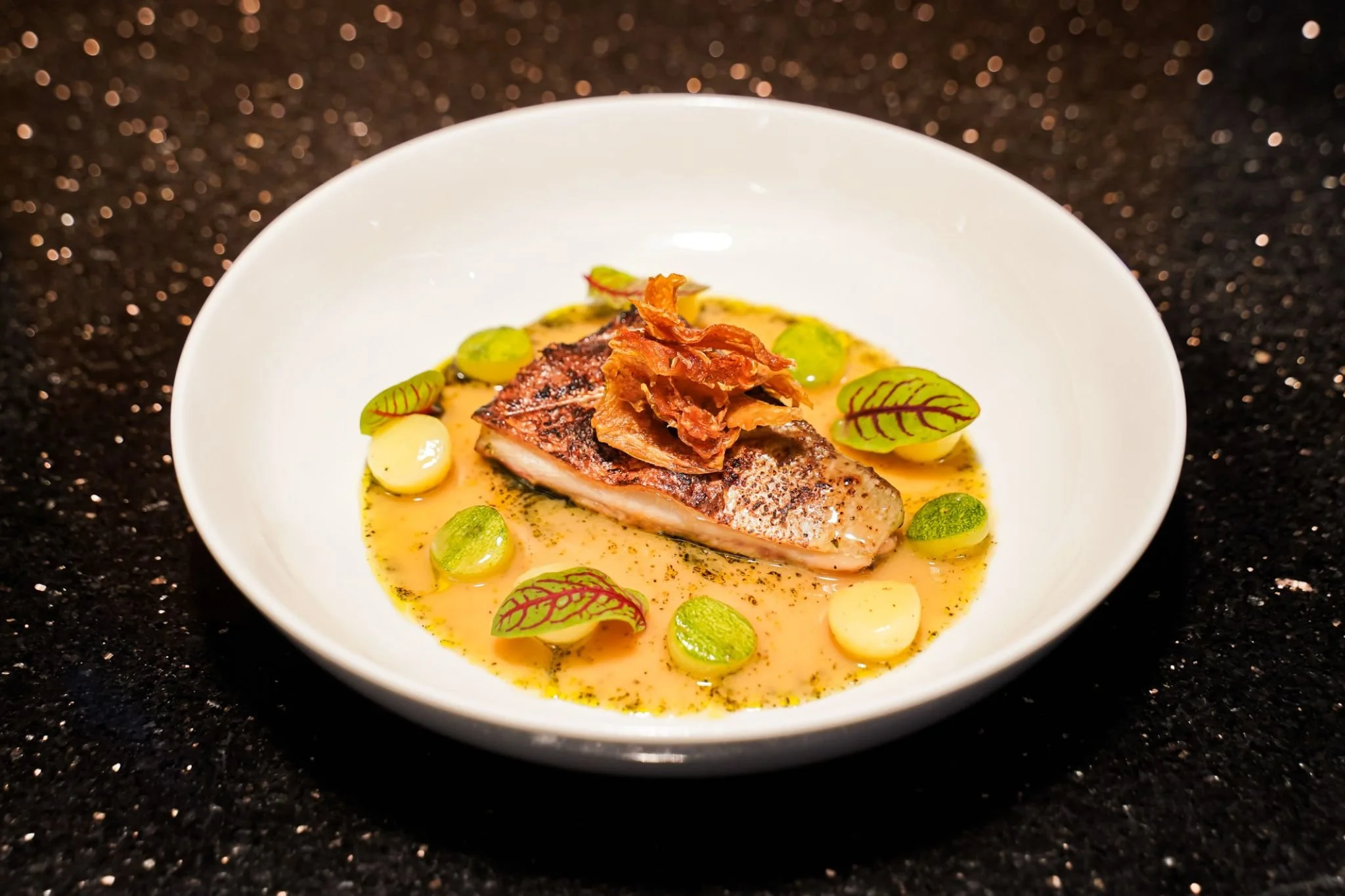 Hamachi Yellowtail Steak
Grilled Hamachi served with Miso Lemon Butter, Artichoke Chips, Nori Oil, Potato Pearls and Zucchini Pearls

Стейк из хамачи (жёлтохвоста)
Хамачи на гриле с мисо-лимонным маслом, чипсами из артишока, маслом нори, картофельным