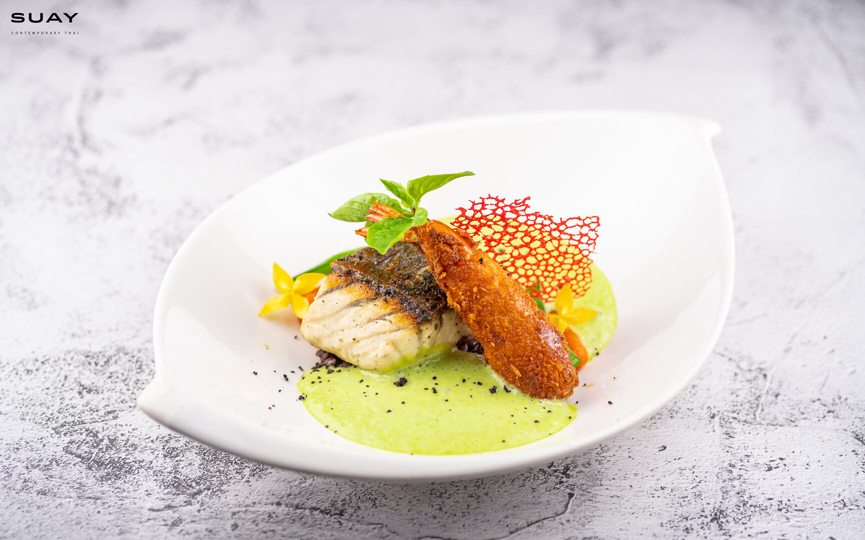 Sea bass steak with green curry, young coconut black rice risotto, and crispy coconut crawn.