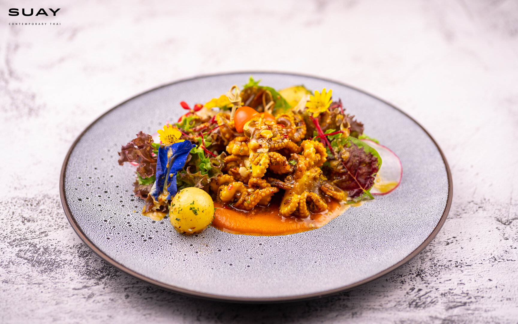 Grilled baby octopus with peanut and sweet chili dressing, served with bell pepper and carrot puree, pomelo and basil salad.