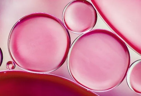 Close-up of pink and clear oil or water bubbles in a liquid.