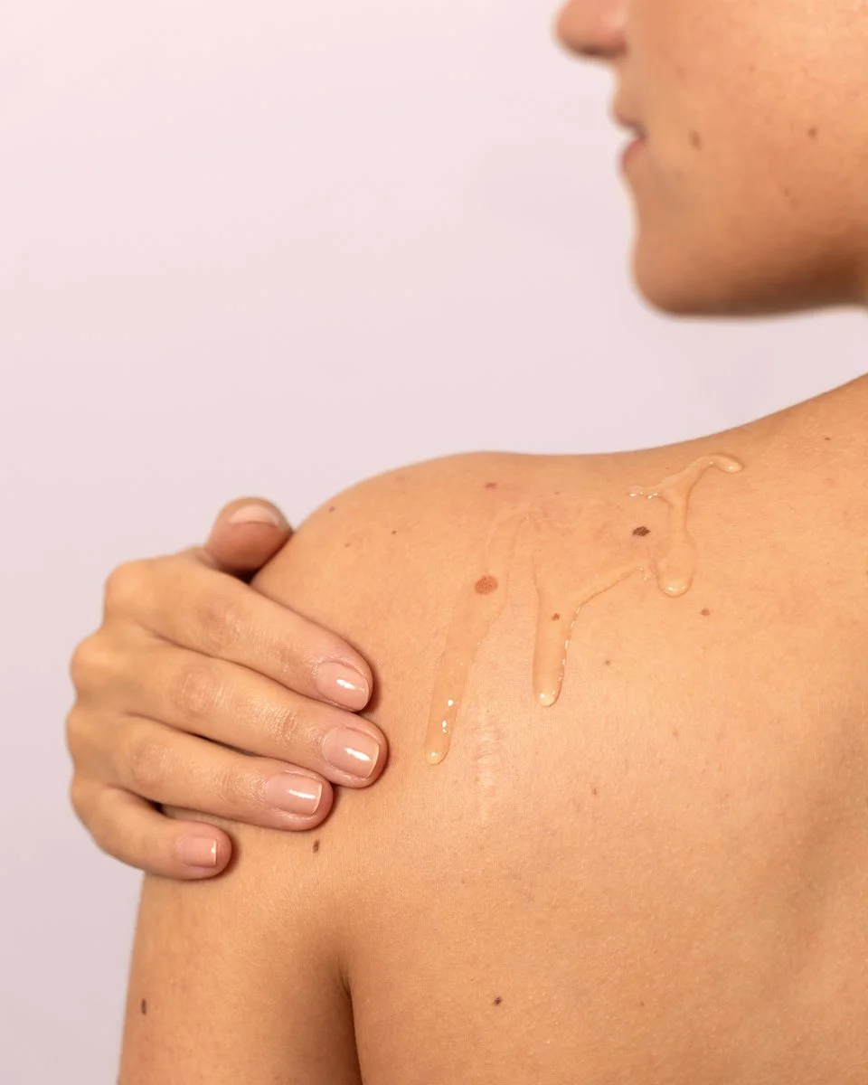 Close-up of a person's shoulder with body oil being rubbed into the skin.