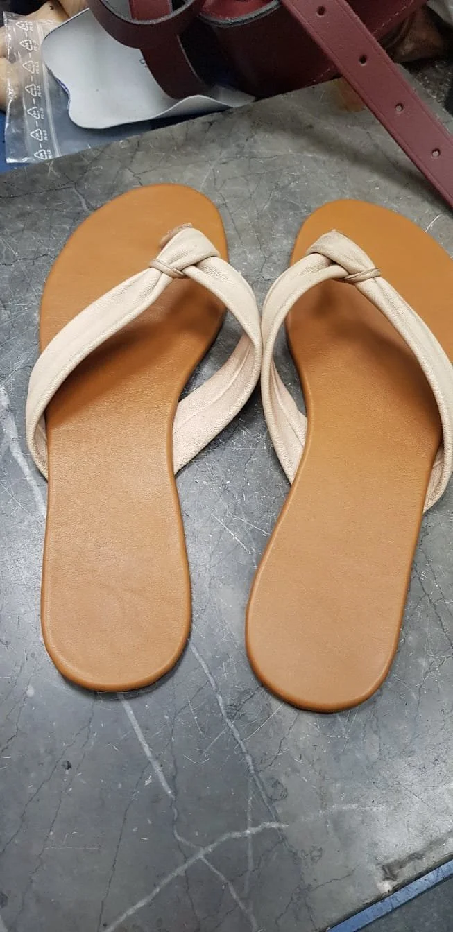 Ein Paar beigen Sandalen auf einem grauen, marmorierten Boden.