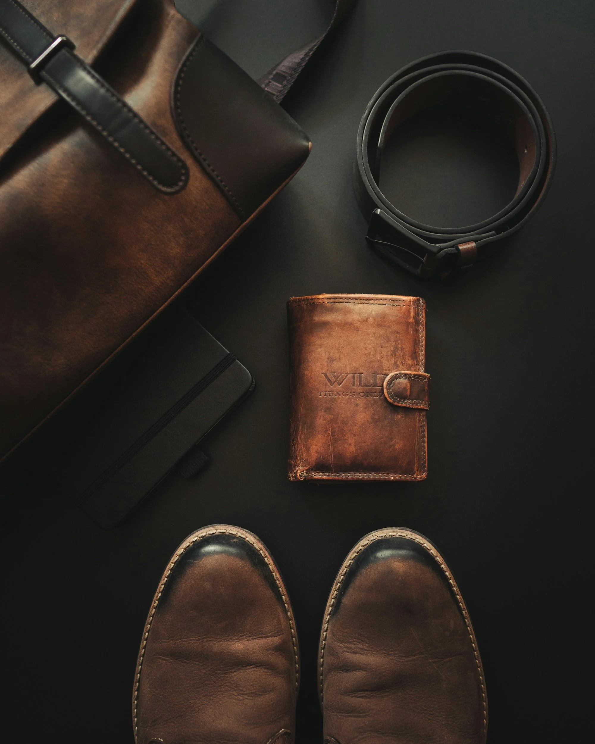 Blick auf das Paar Schuhe eines Menschen, die stehende Person trägt braune Schuhe mit weißen Sohlen, obere Sicht, auf schwarzem Boden.