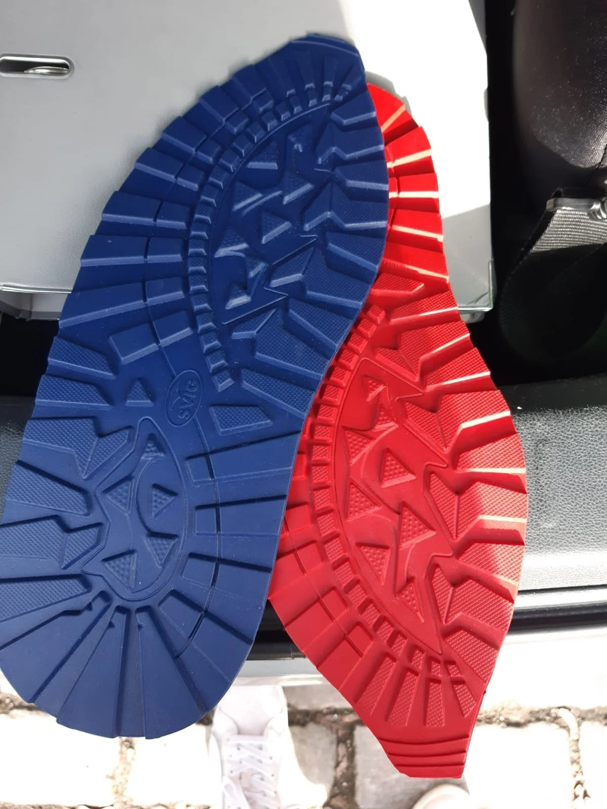 Bunte Gummisohlen in Blau und Rot, die auf einer Oberfläche liegen.
