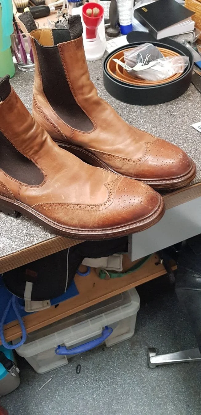 Lederschuhe mit Hacken und Schnürung, braun und schwarz, auf einem Arbeitstisch