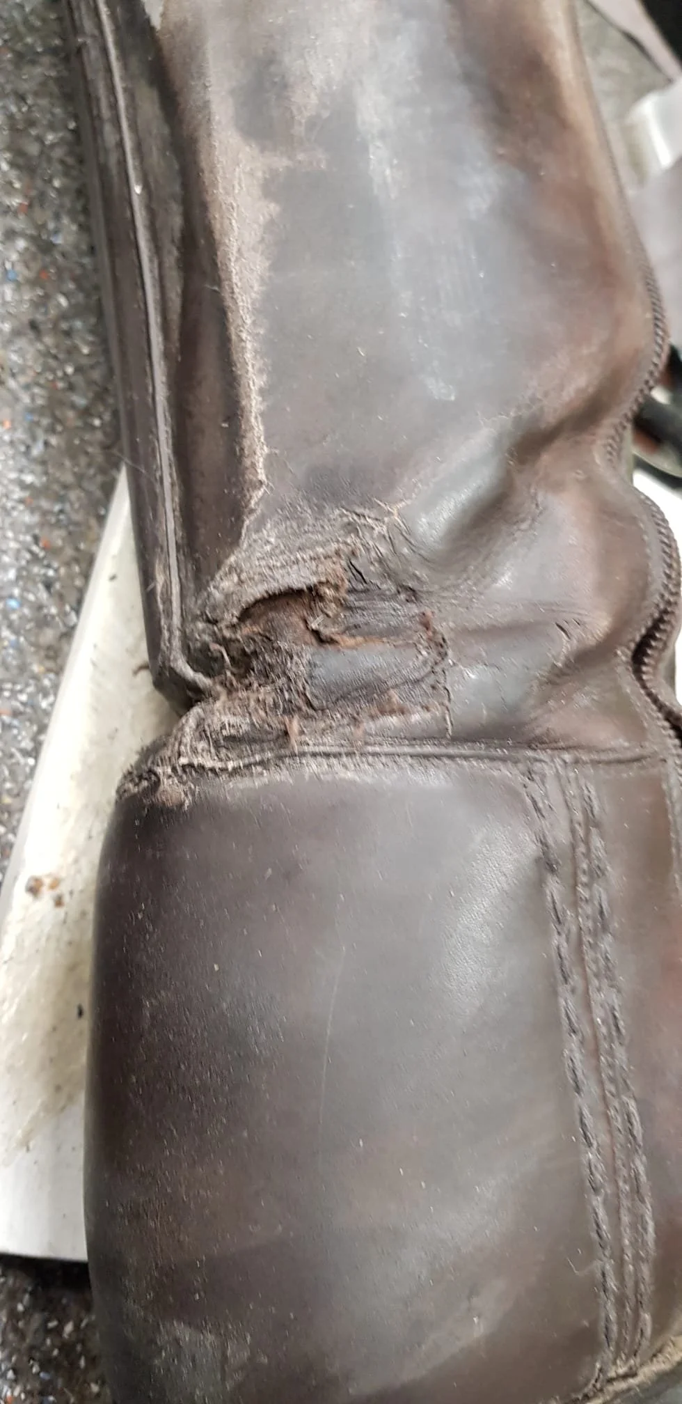Abgenutzter und beschädigter Lederschuh mit sichtbarem Riss und Verschleißstellen im Bereich der Zehenpartie.