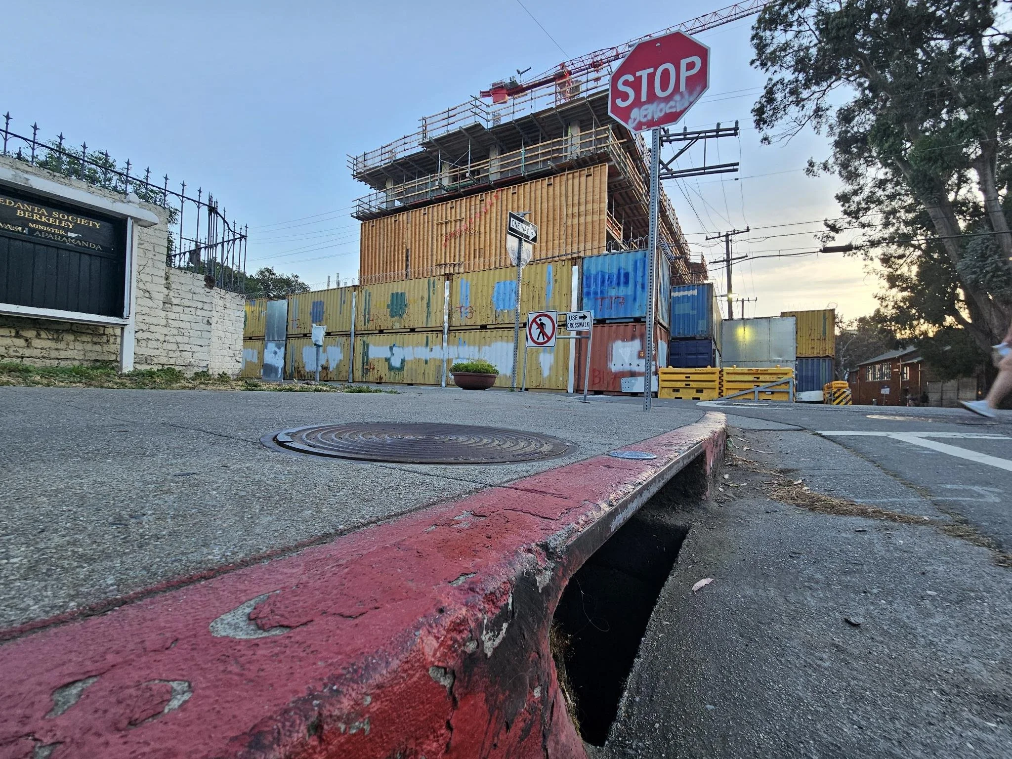 Construction site at a Southside Berkeley street corner with a stop sign and sidewalk.