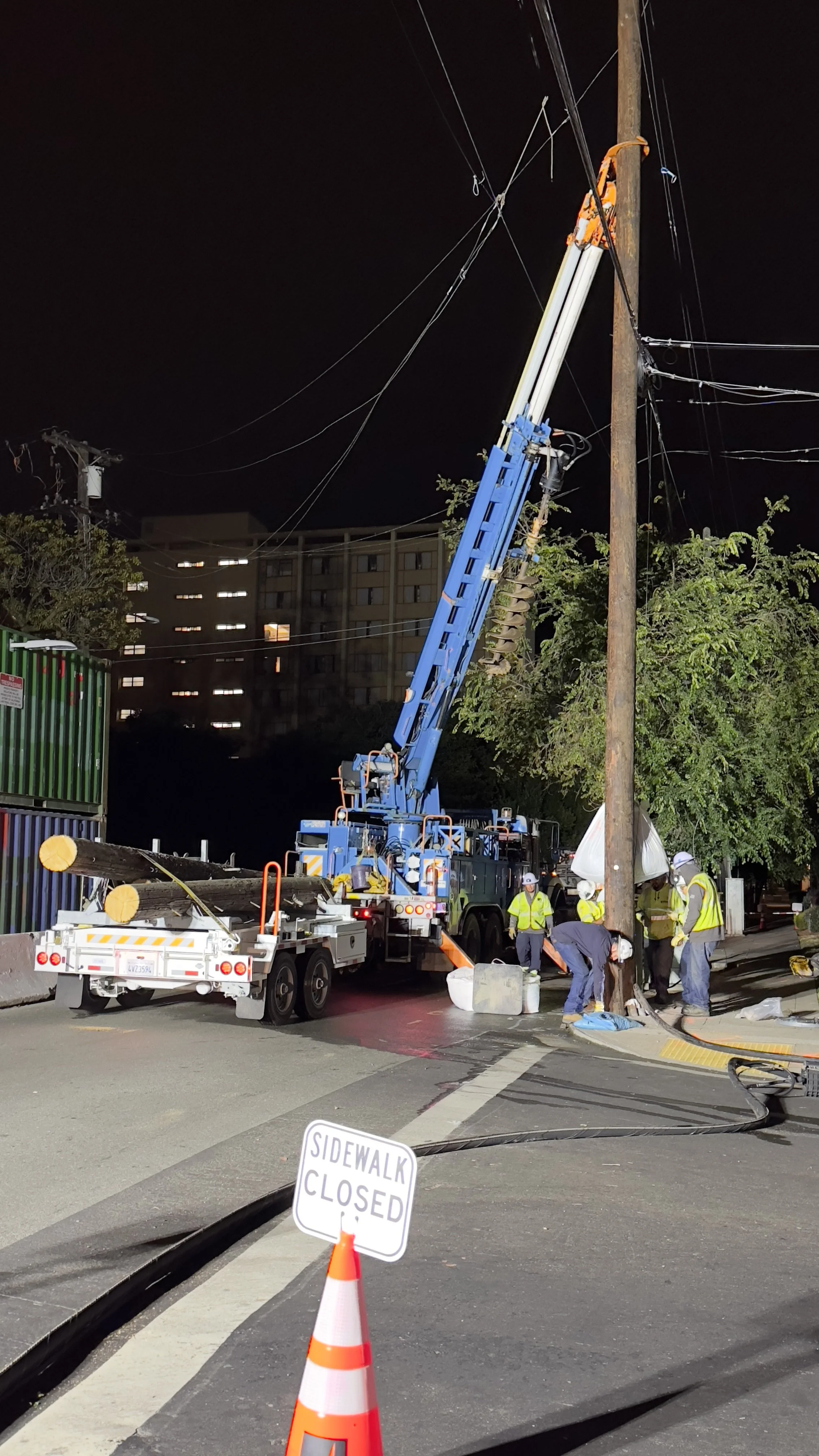 Night construction work in Southside Berkeley with a sidewalk closed sign, utility equipment, workers, and street infrastructure.