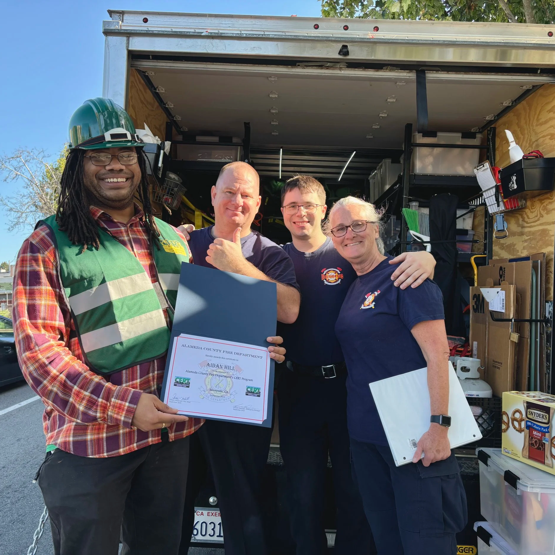 Aidan Hill with community members holding an Alameda County Fire Department CERT Program certificate.